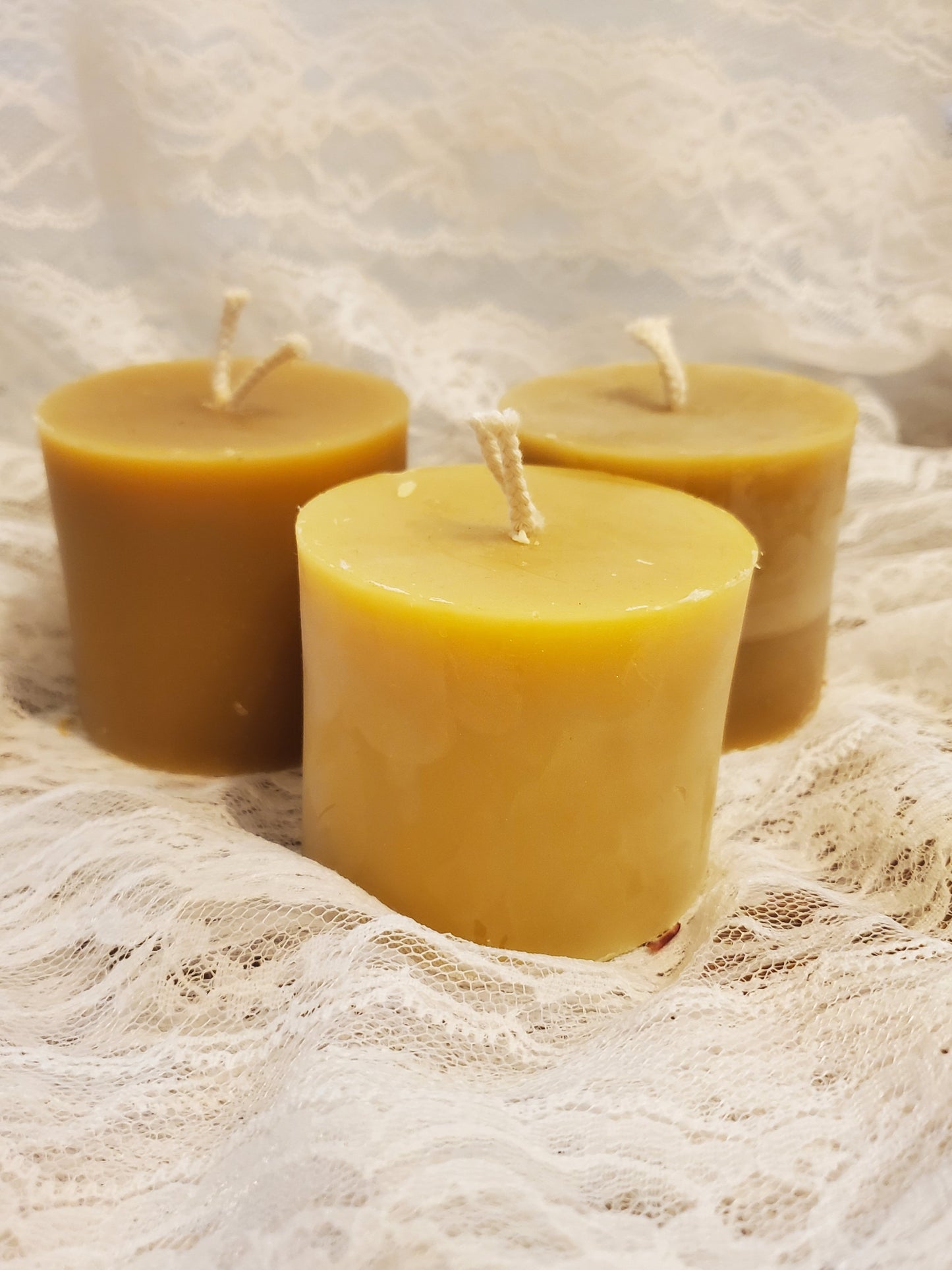 Three beeswax candles on a textured white surface