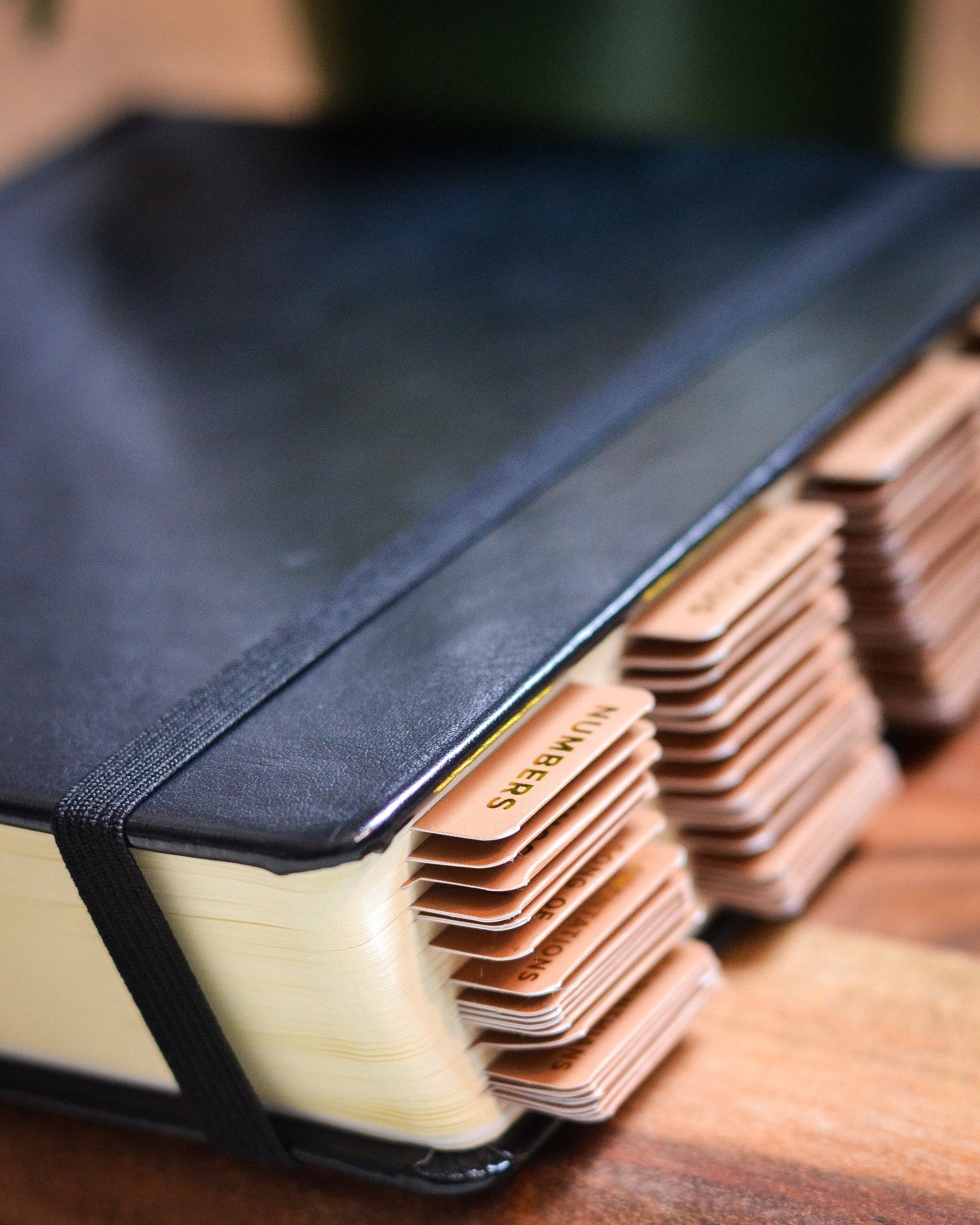 Stack of black-bound books with visible cardstock pages on a wooden surface