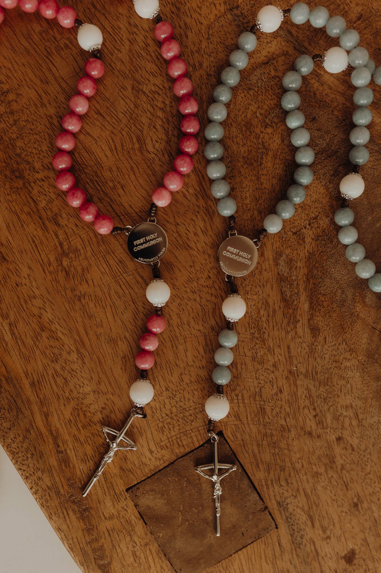 Two beaded rosarys with cross pendants on a wooden surface