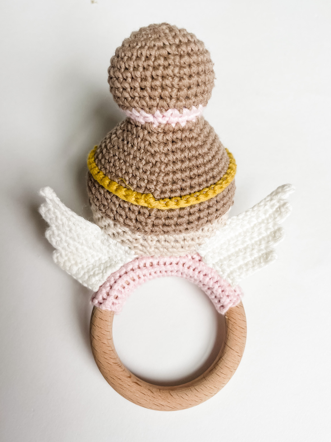 Crocheted rattle with wooden ring on a white background