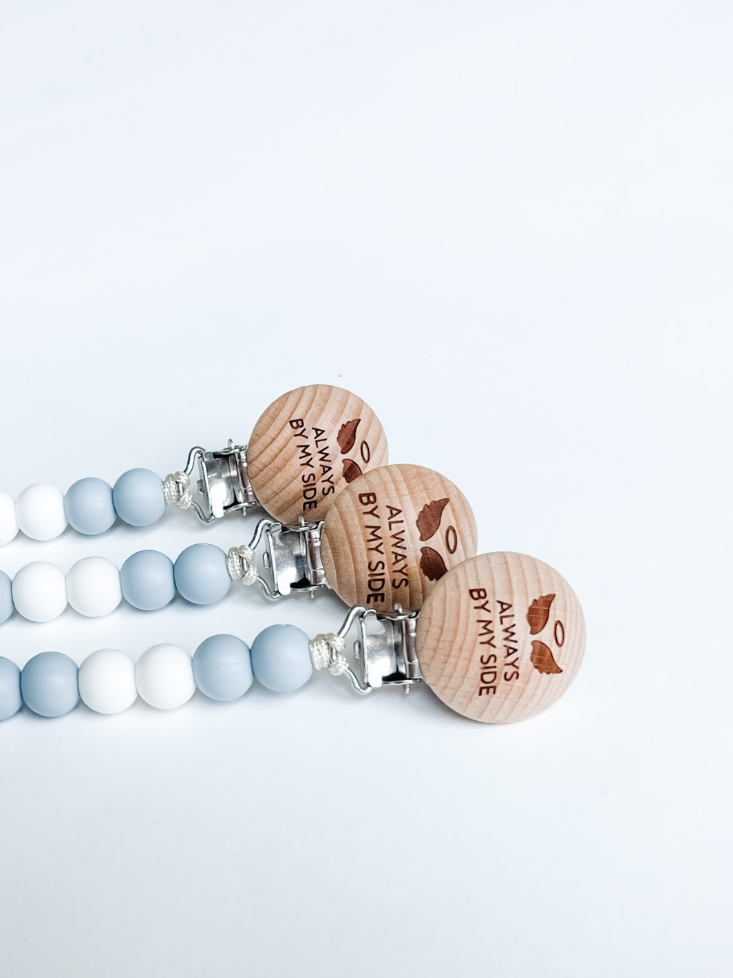 Set of baby teething necklaces with wooden beads and engraved text on a light blue background