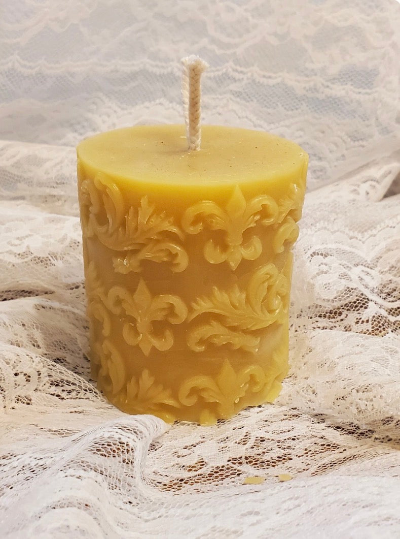 Decorative beeswax candle with intricate patterns on a lace fabric background