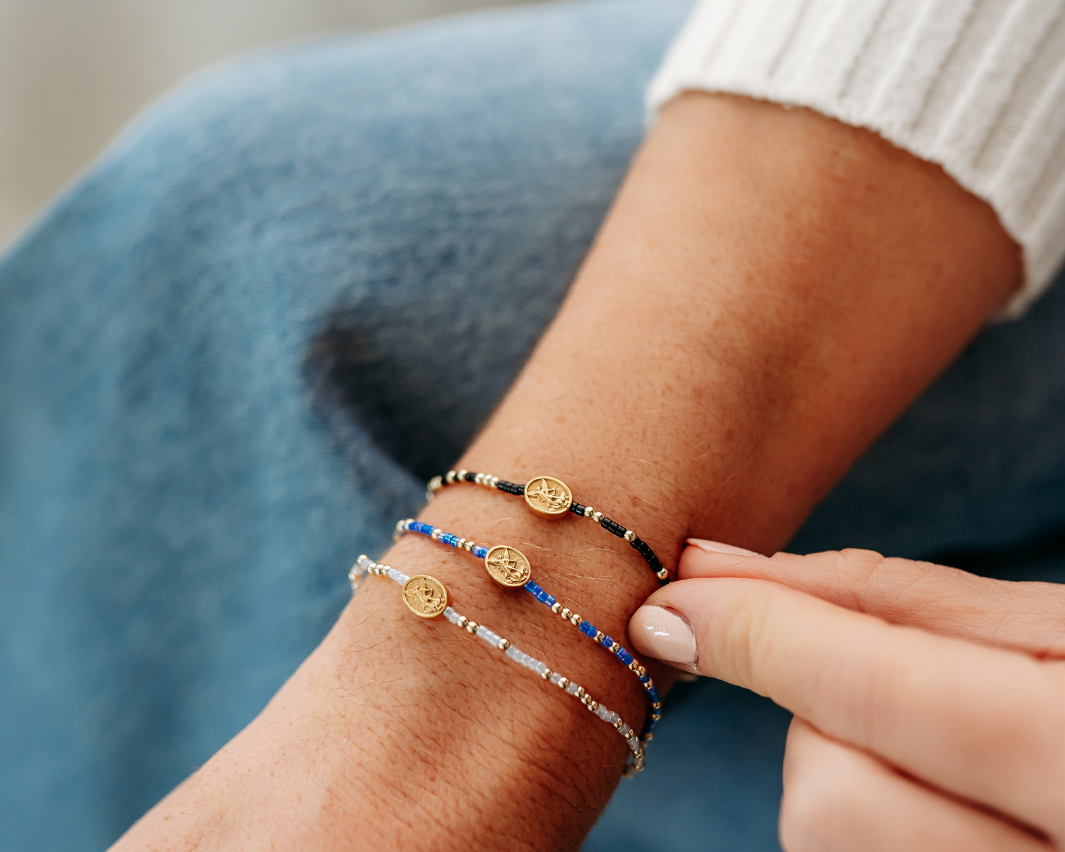 Close-up of a person's wrist wearing multiple bracelets with blue, gold, and silver accents.