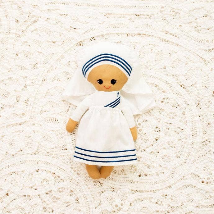 Toy doll in a white dress with blue stripes on a textured beige background