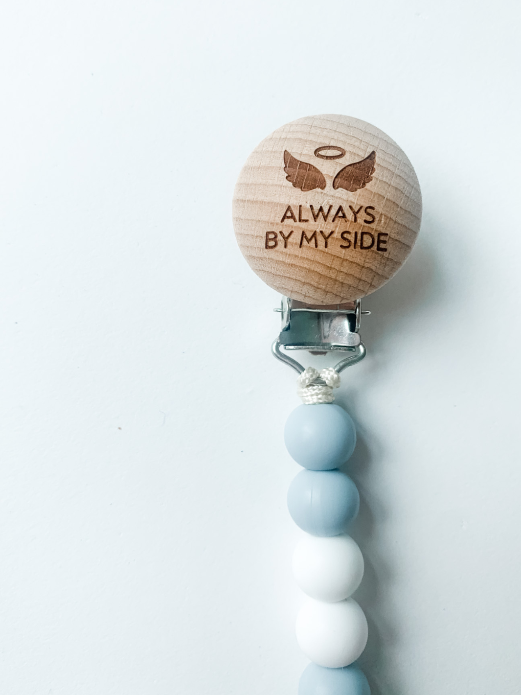 Wooden pacifier clip with blue and white beads on a white background