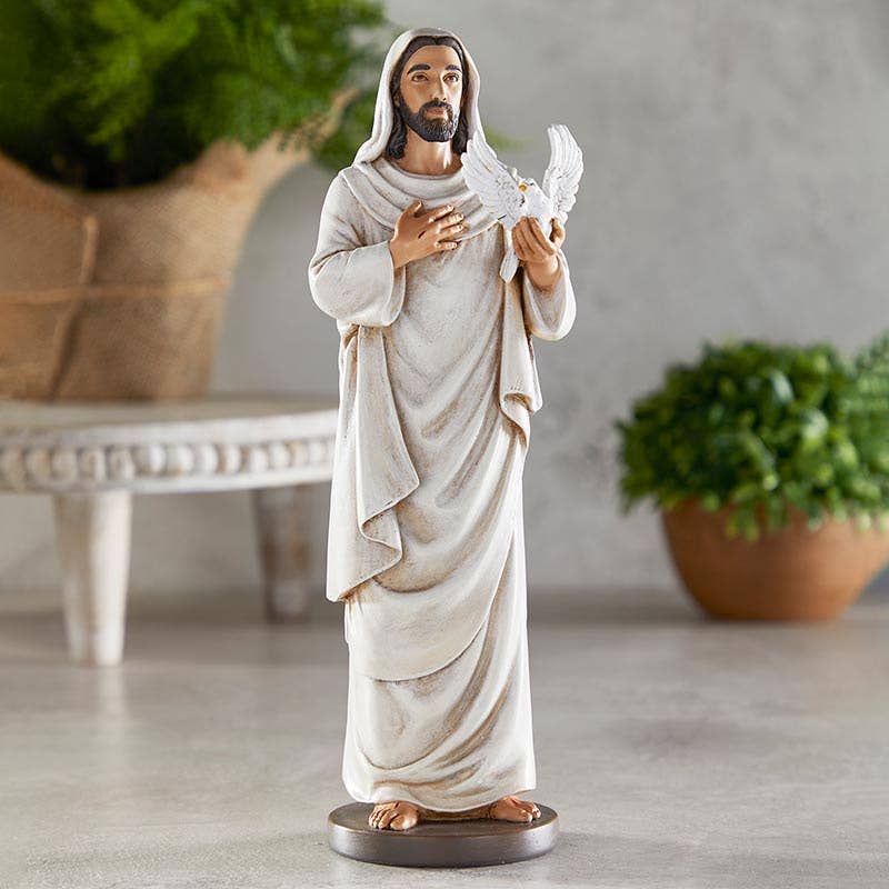 Statue of a jesus holding a dove in a home setting with plants.