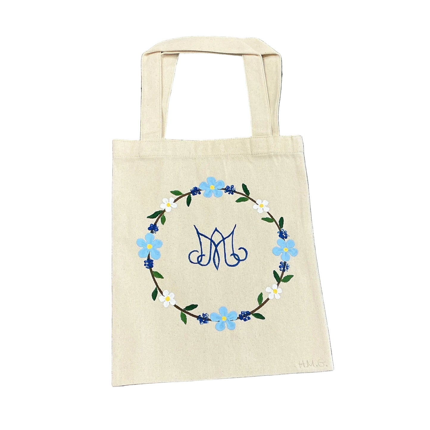 Beige tote bag with floral design on a floral-patterned fabric background