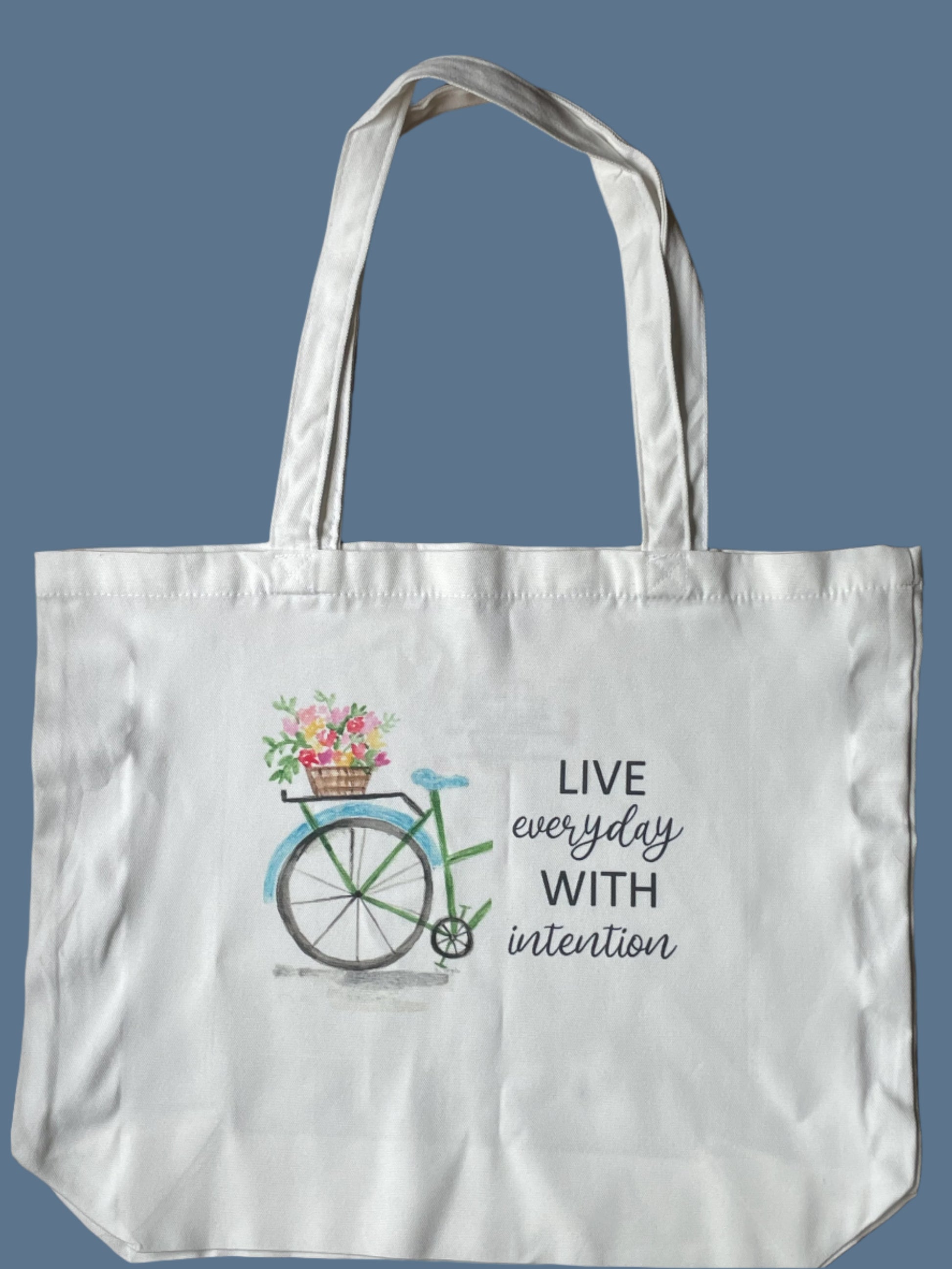 Tote bag with bicycle and flower design on a blue background