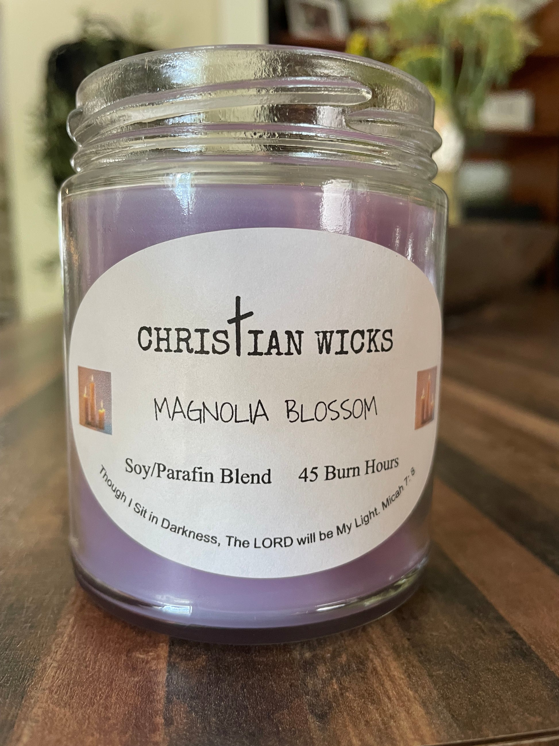 Jar of Magnolia Blossom candle by Christian Wicks on a wooden surface
