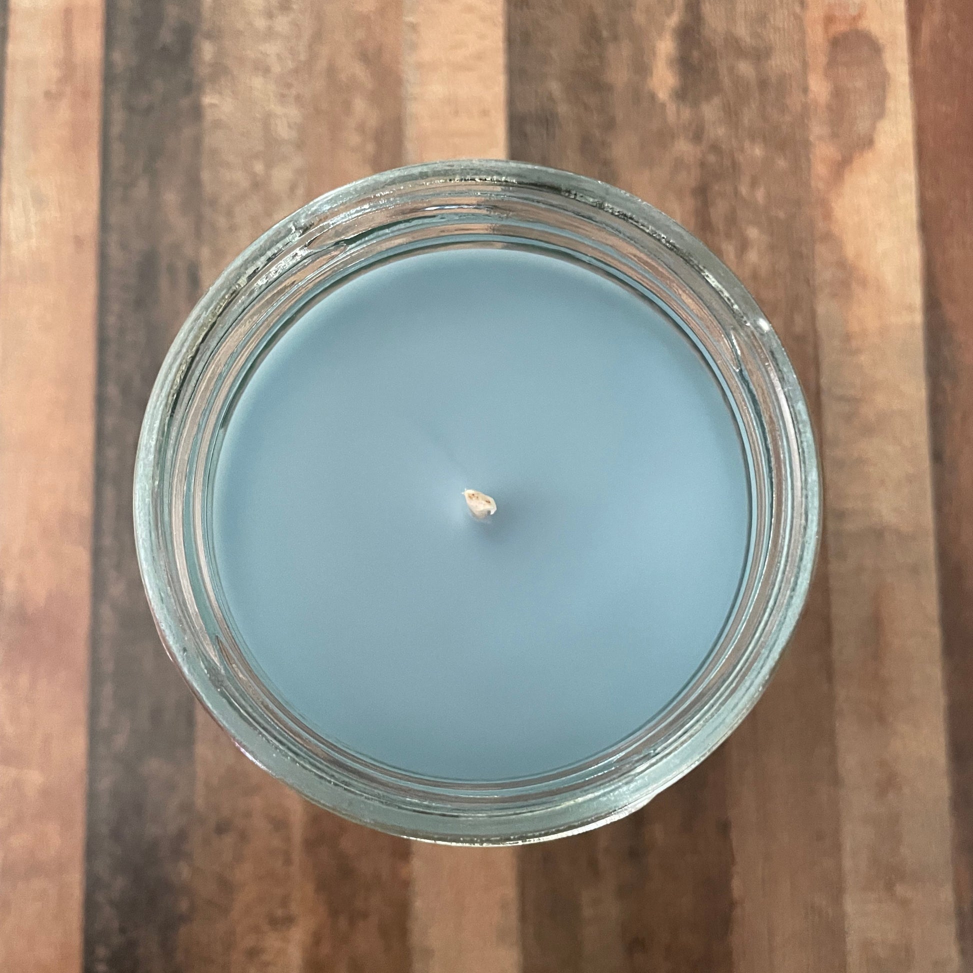 Blue candle in a glass jar on a wooden surface