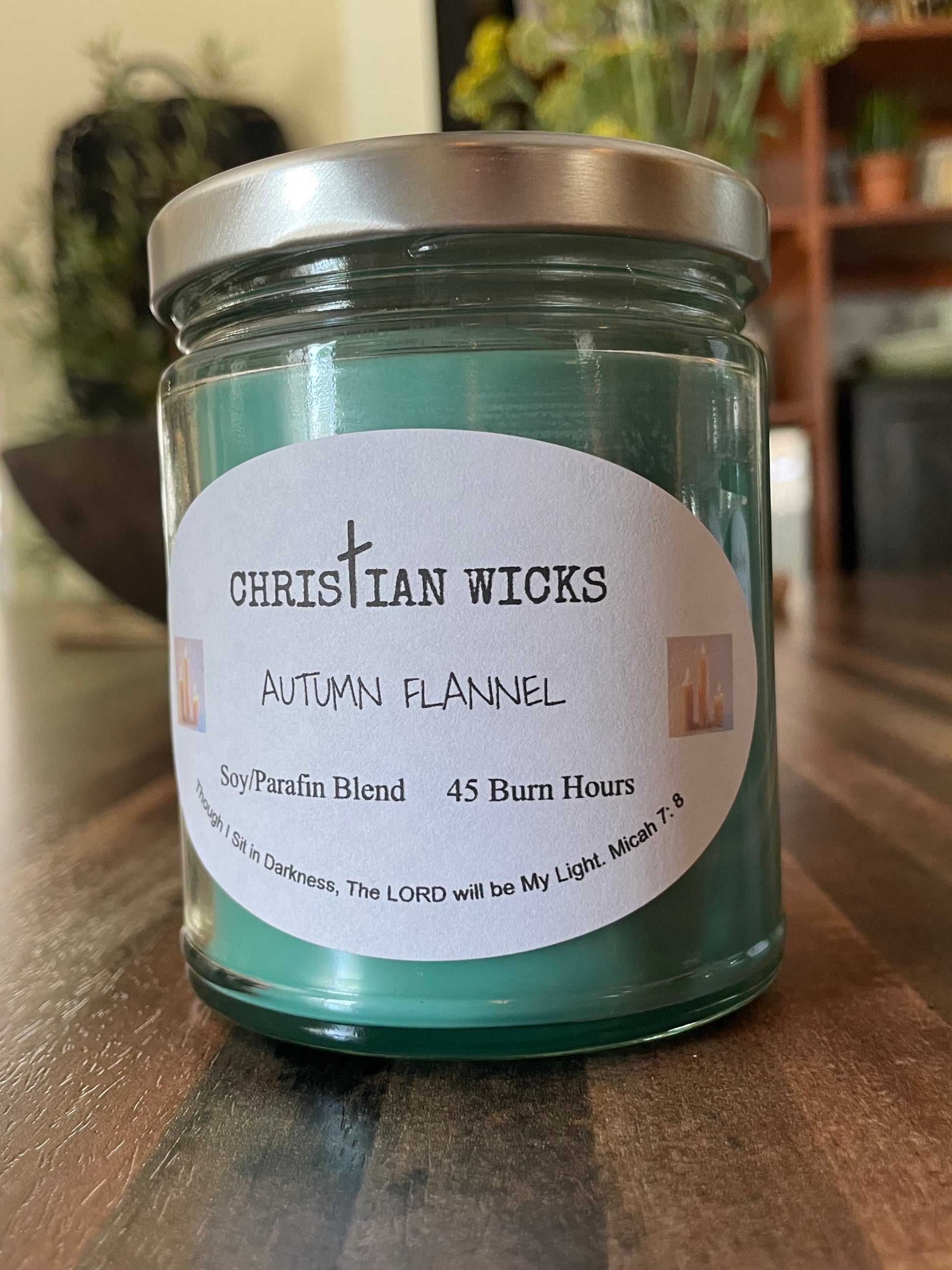 Candle jar labeled 'Autumn Flannel' by Christian Wicks on a wooden surface.
