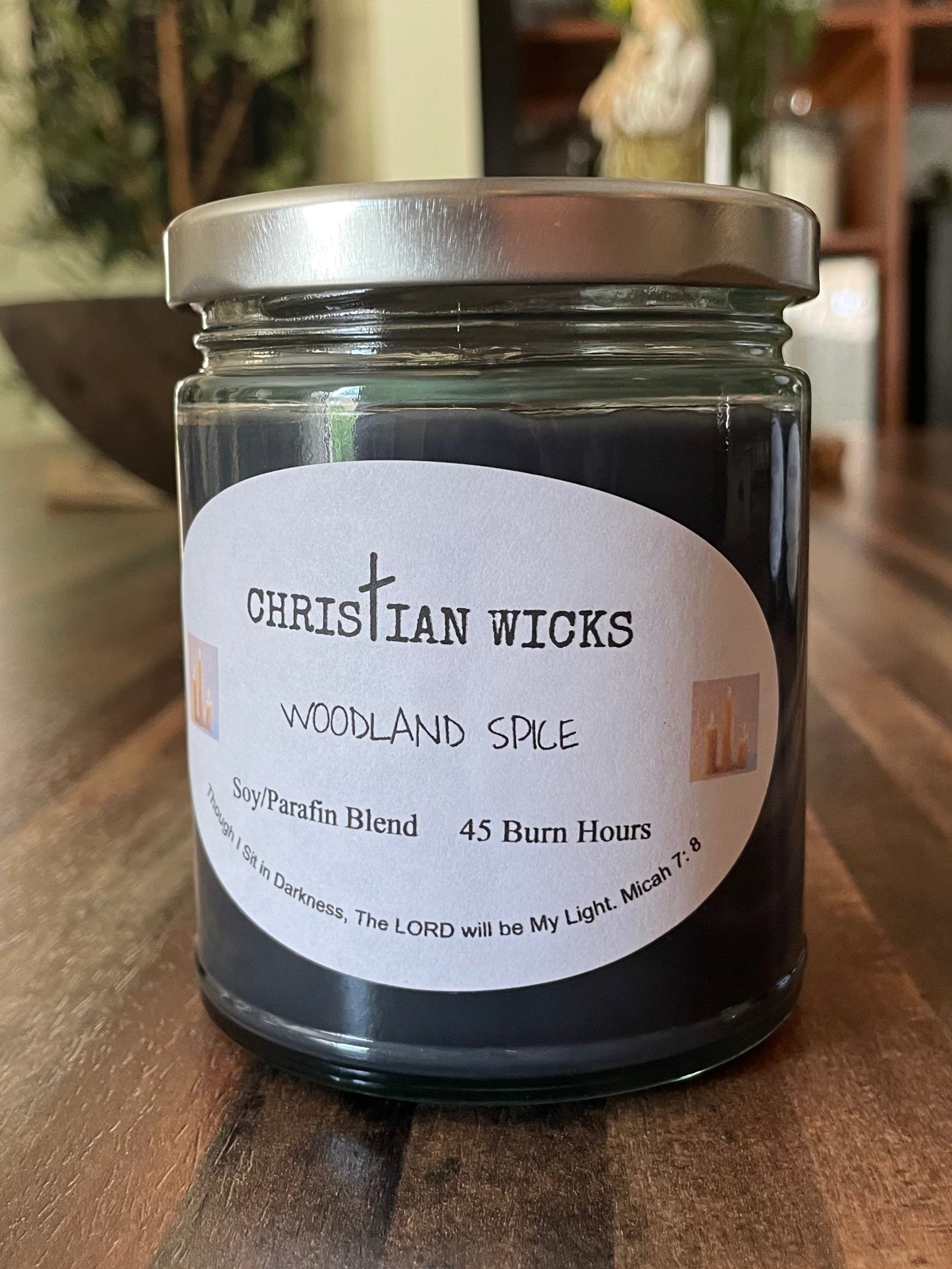 Jar of Christian Wicks Woodland Spice candle on a wooden surface
