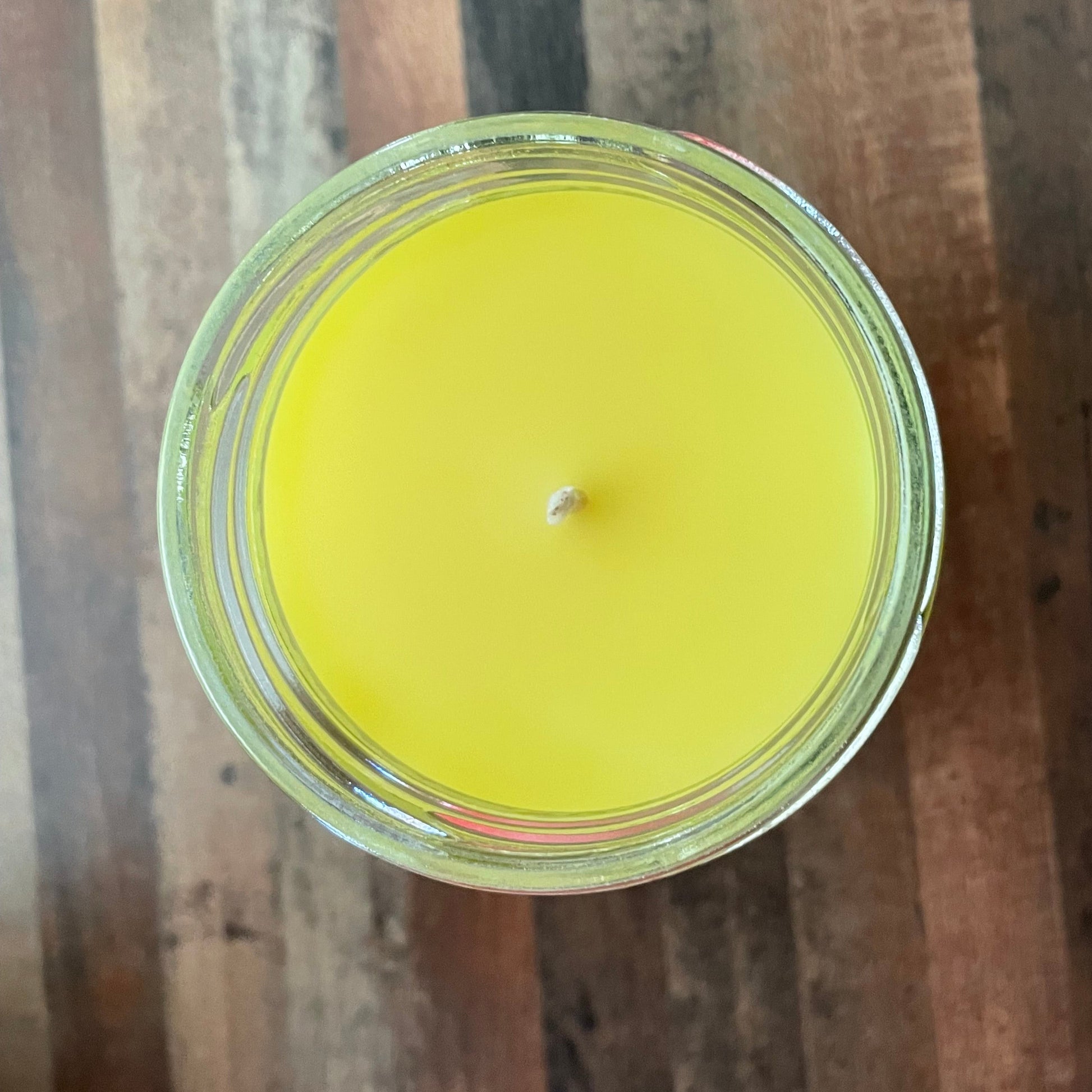 Yellow candle in a glass jar on a wooden surface