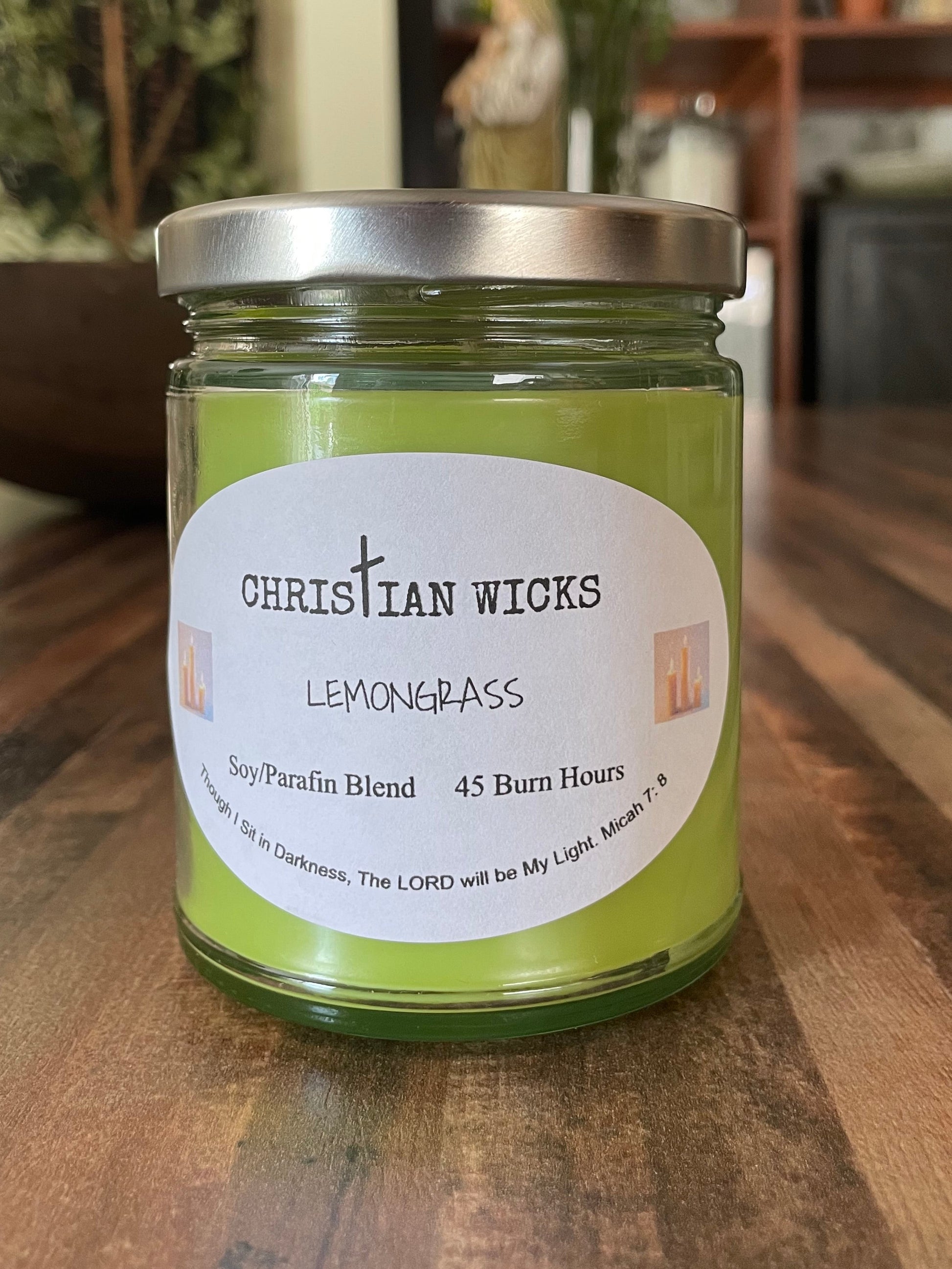 Green lemongrass candle in a jar with a label on a wooden surface