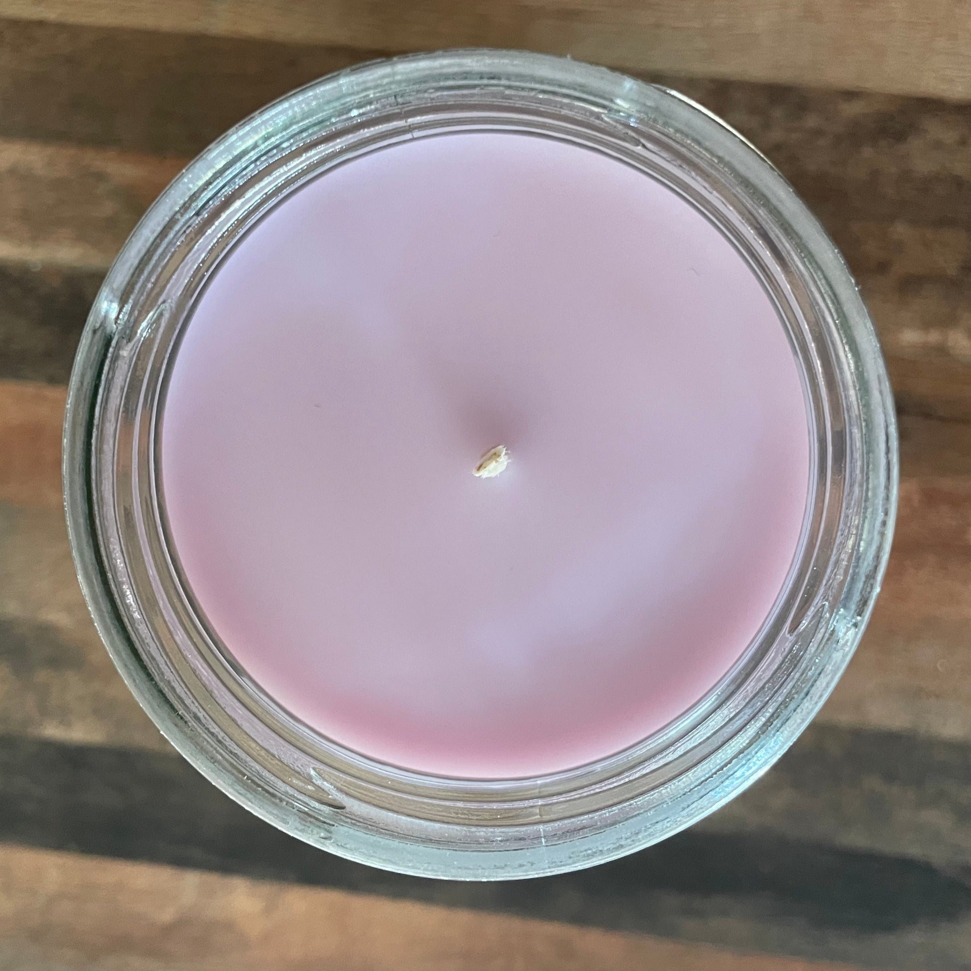 Lavender candle in a glass jar on a wooden surface