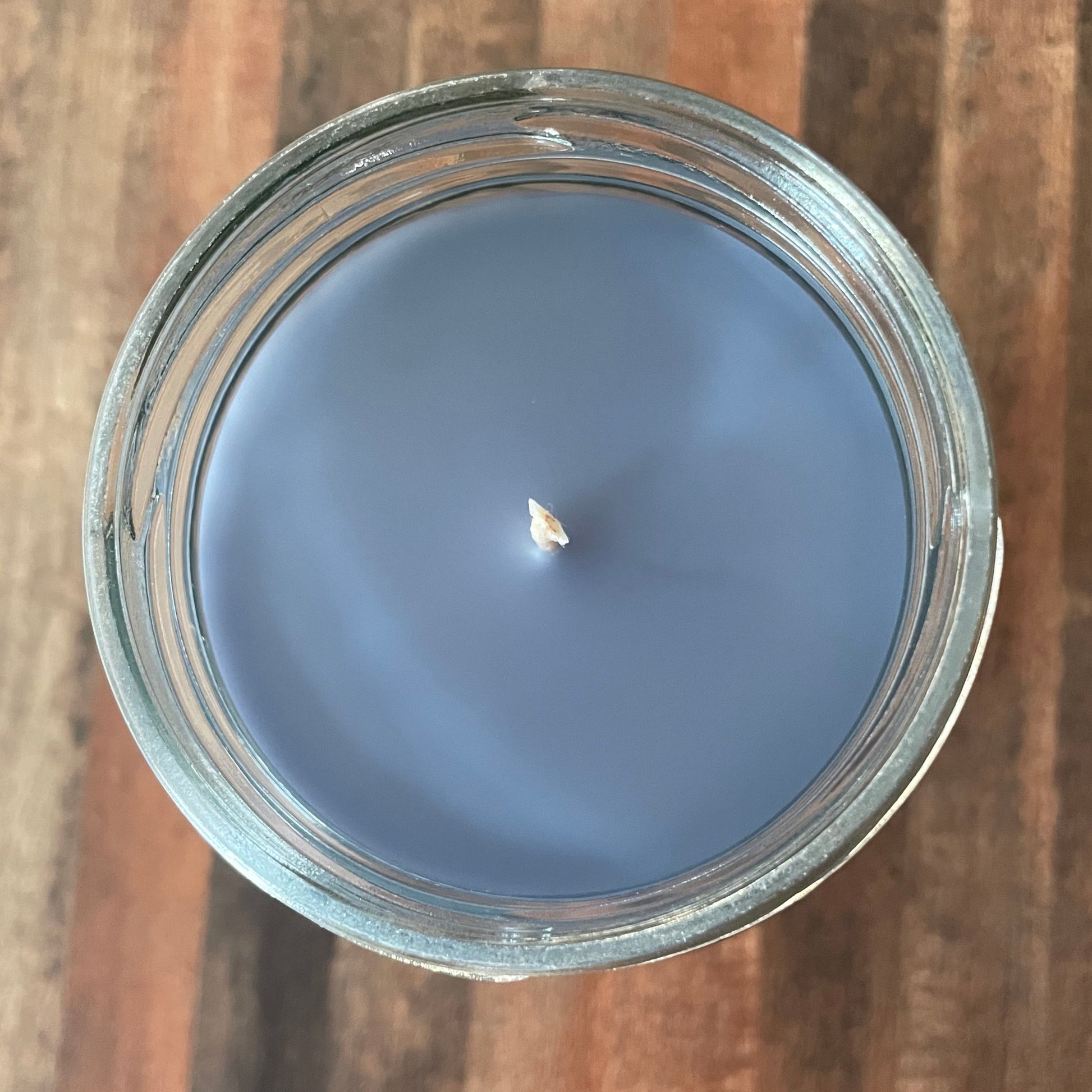 Blue candle in a glass jar on a wooden surface