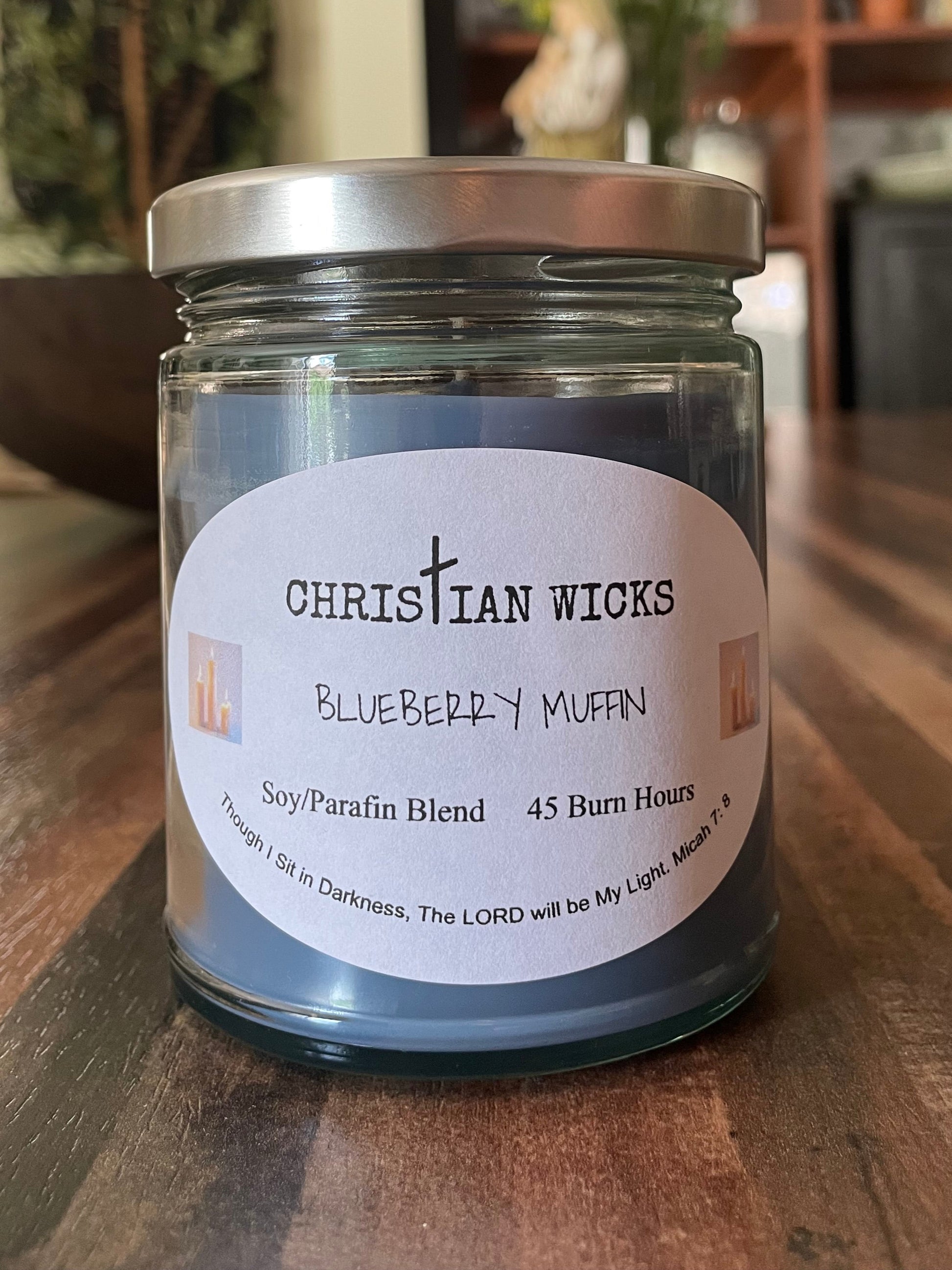 Jar of ChristIan Wicks blueberry muffin candle on a wooden surface with a blurred background