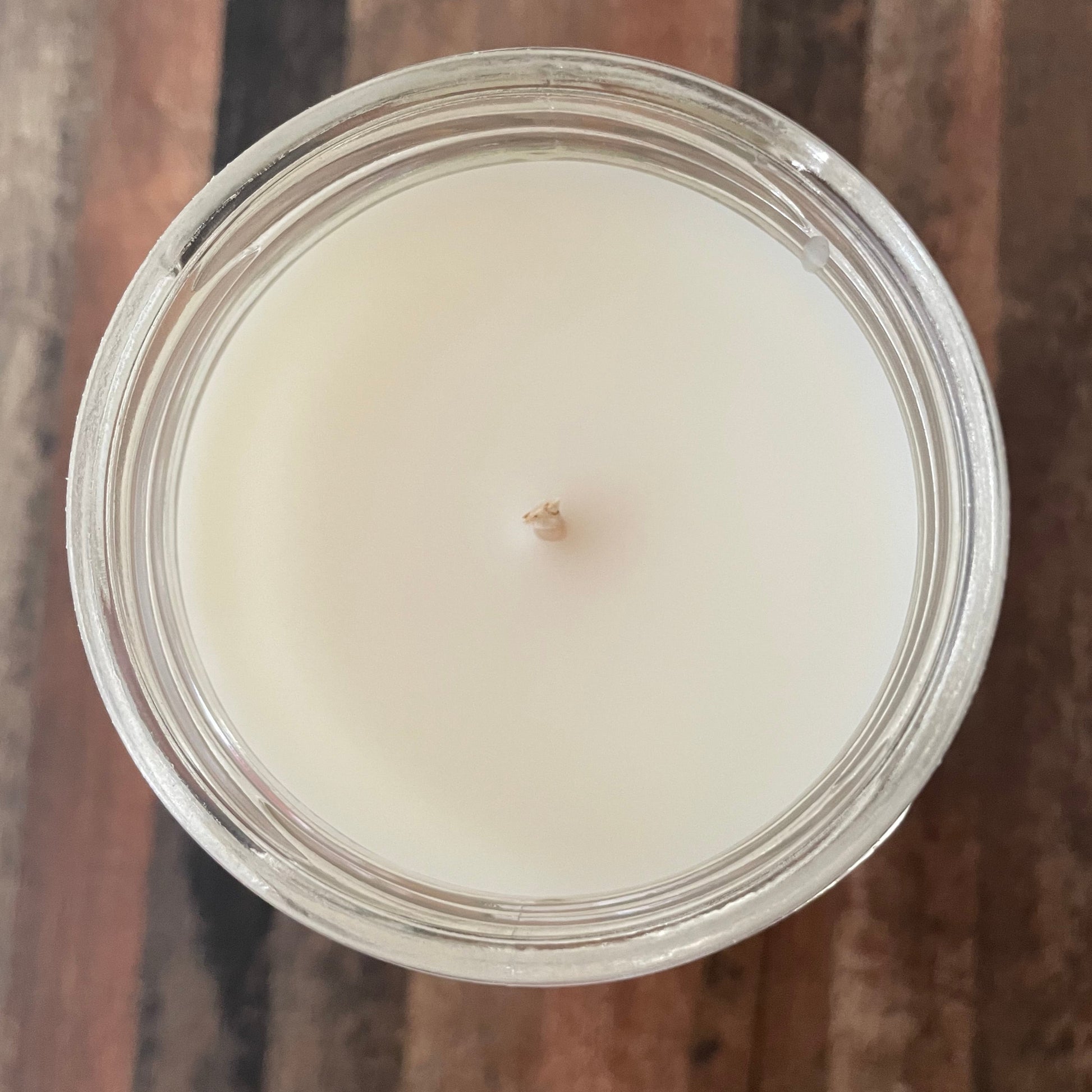Candle in a glass jar on a wooden surface