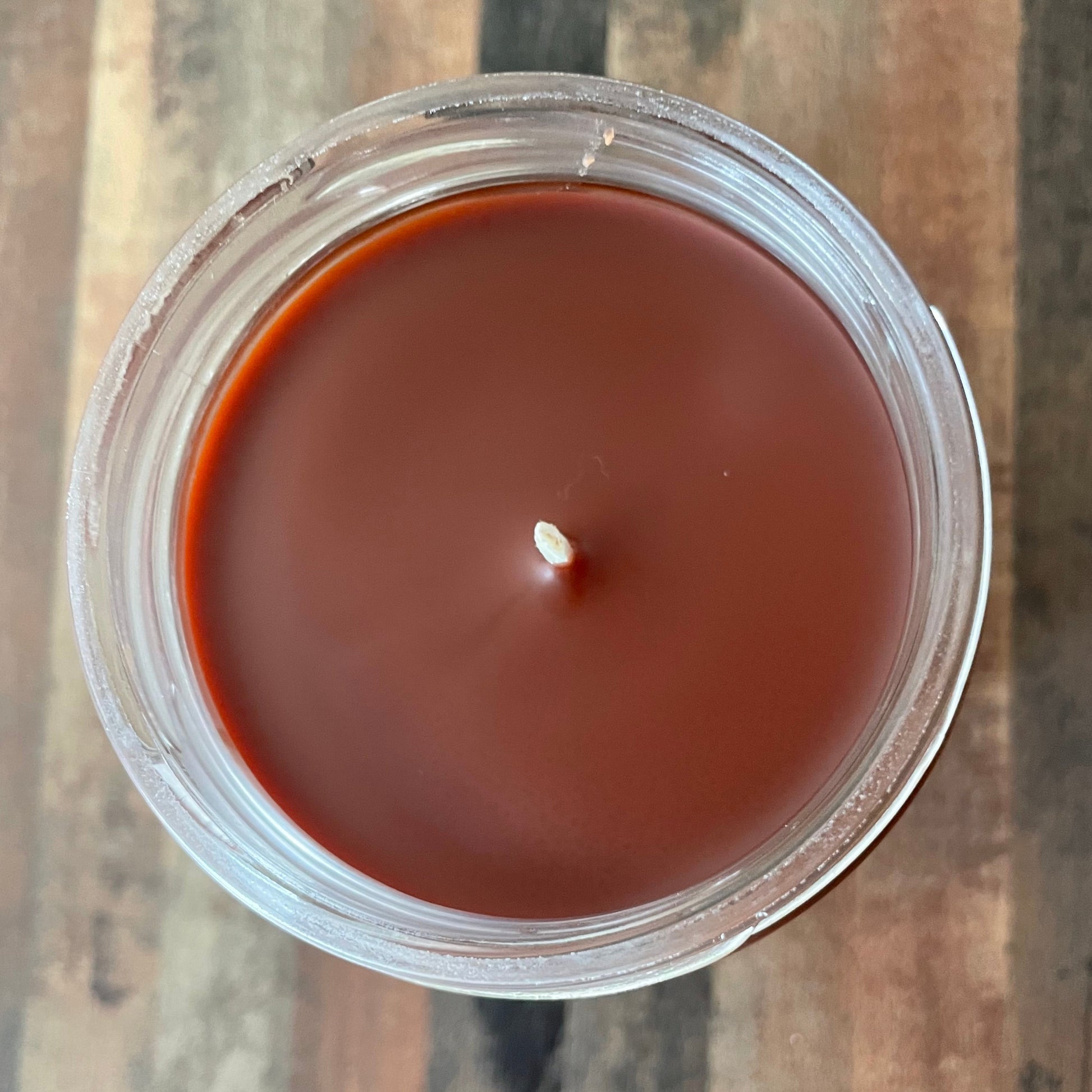 Candle in a glass jar on a wooden surface