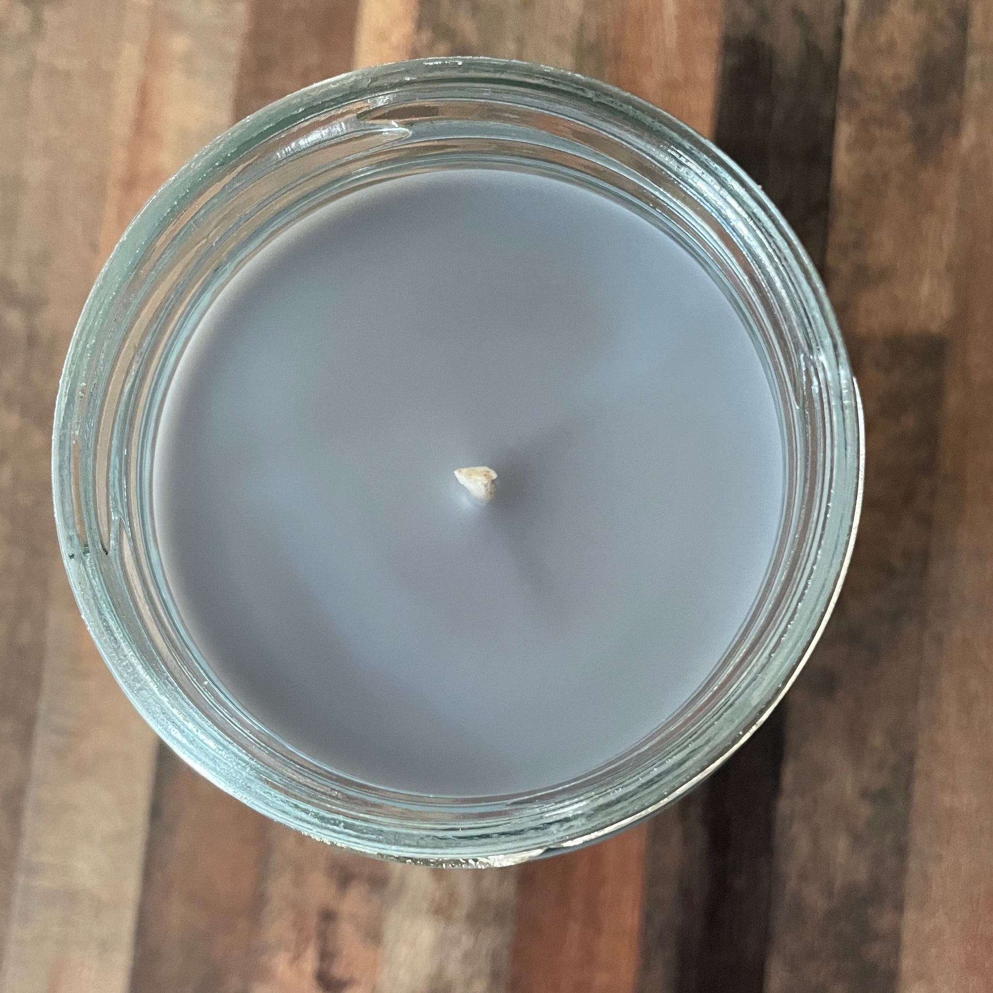 Candle in a glass jar on a wooden surface