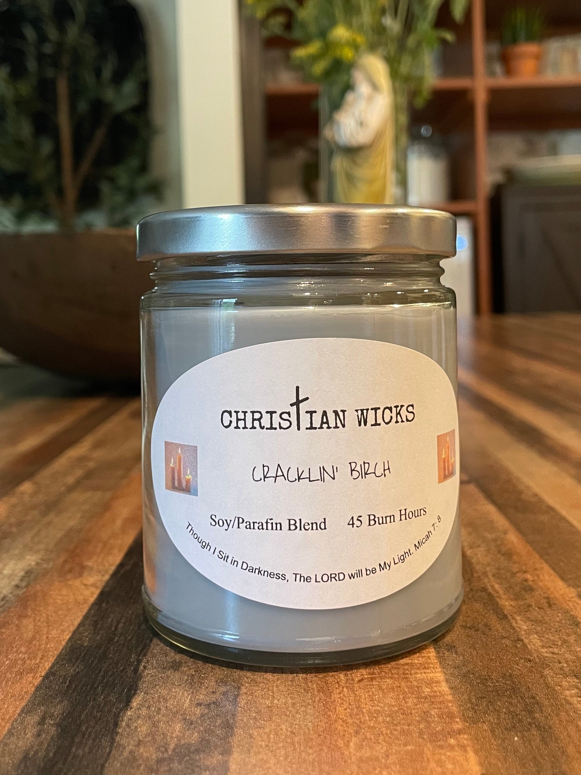 Jar of Christian Wicks crackin birch candle on a wooden surface with a blurred indoor background