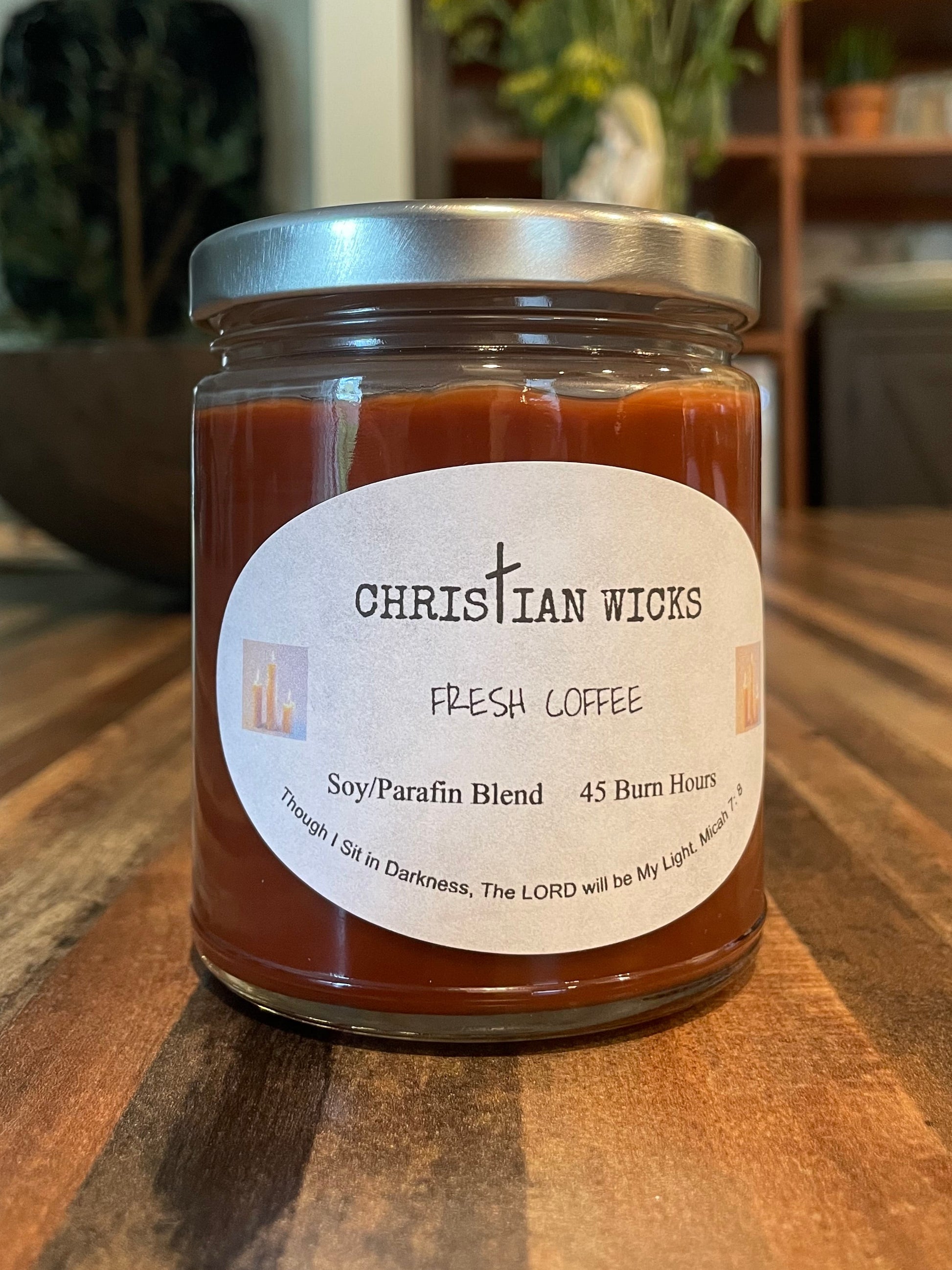 Jar of coffee candle by Christian Wicks on a wooden surface with a blurred background