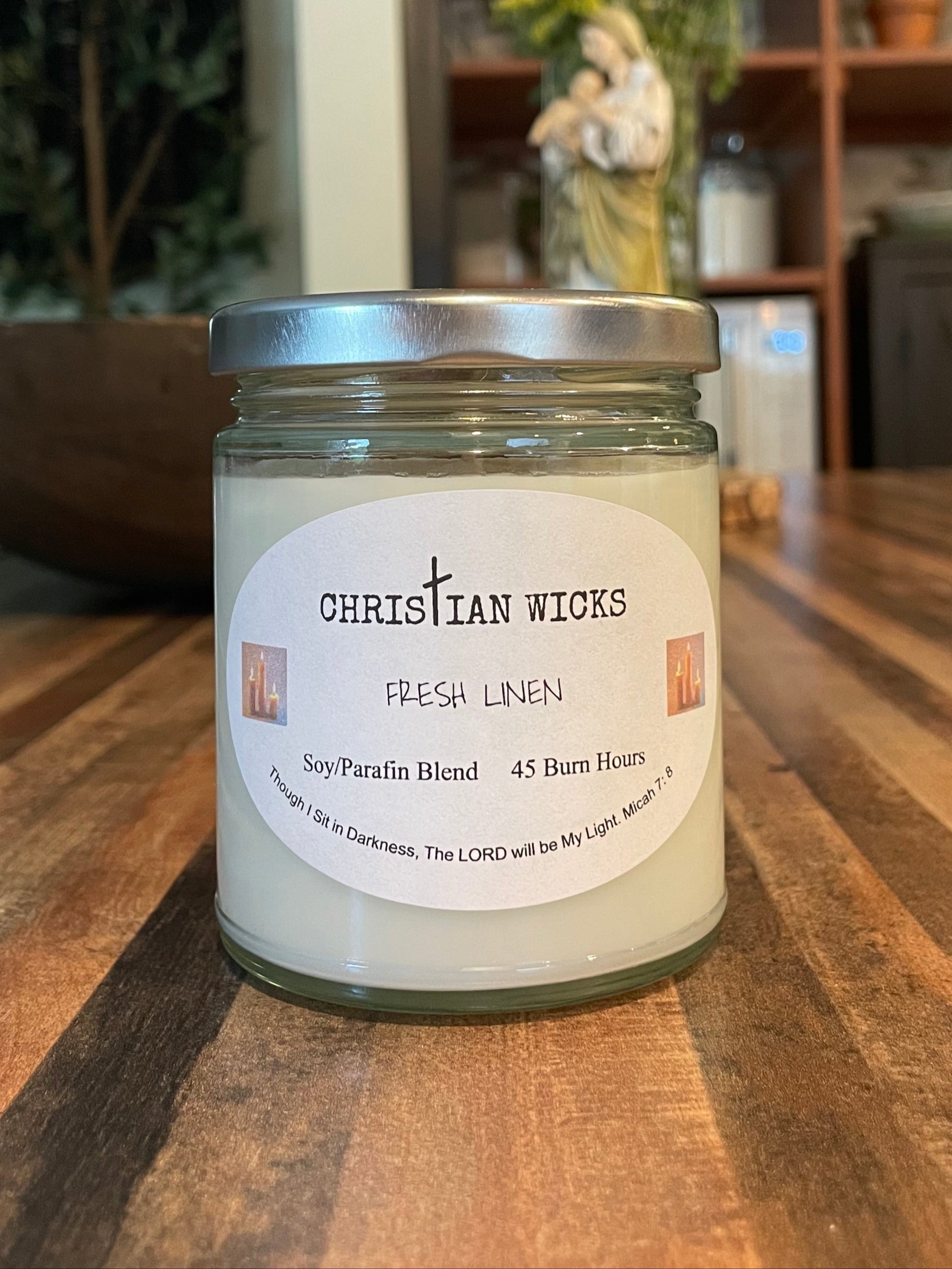 Jar of fresh linen candle by Christian Wicks on a wooden surface