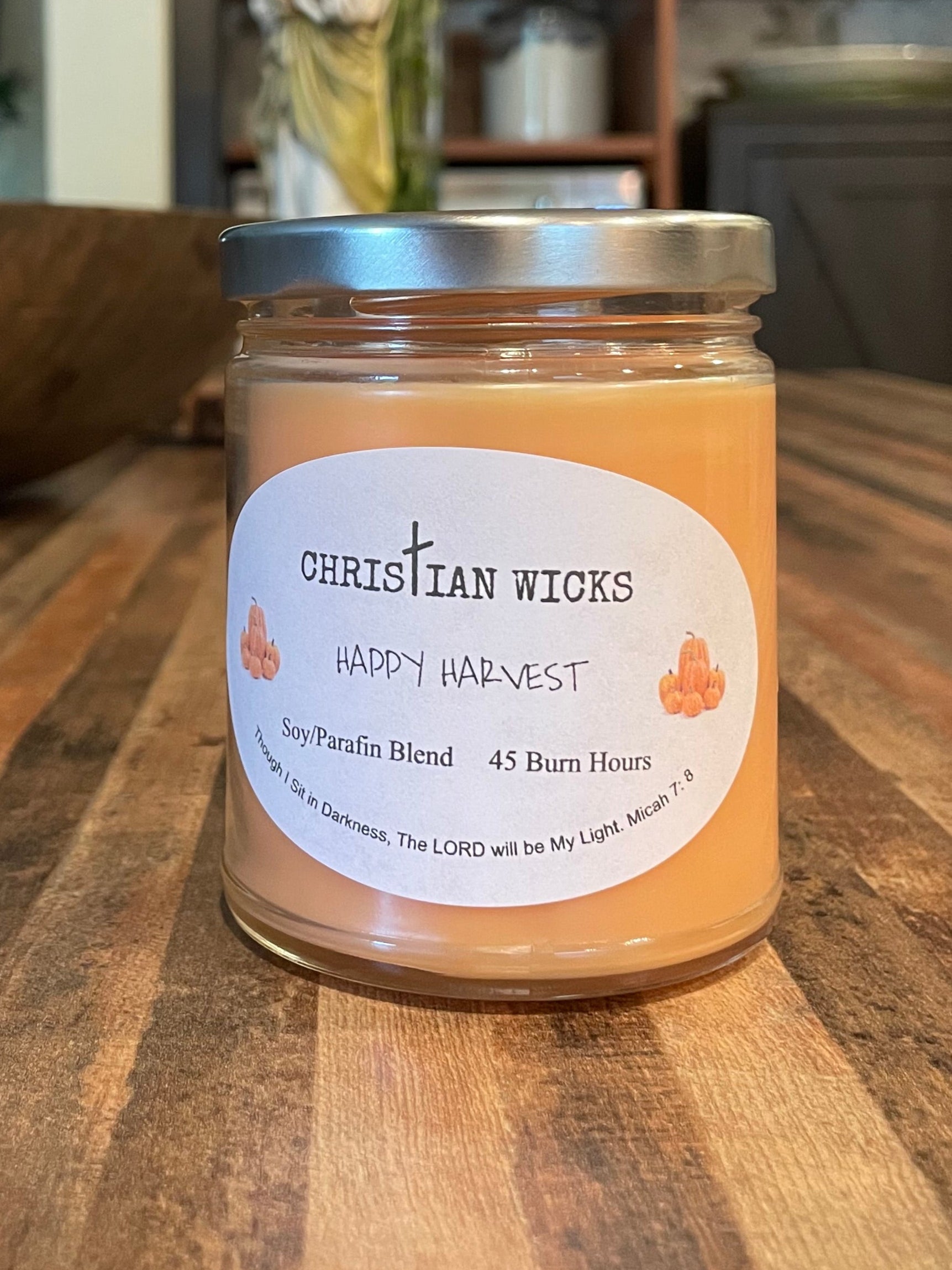 Jar of candle wax on a wooden surface with a blurred indoor background