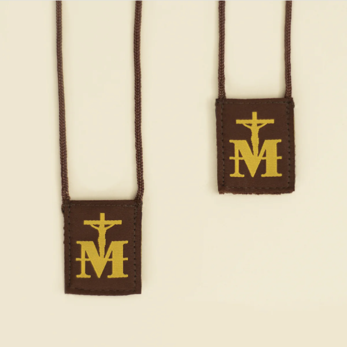Scapulars with cross and 'M' symbol on a beige background