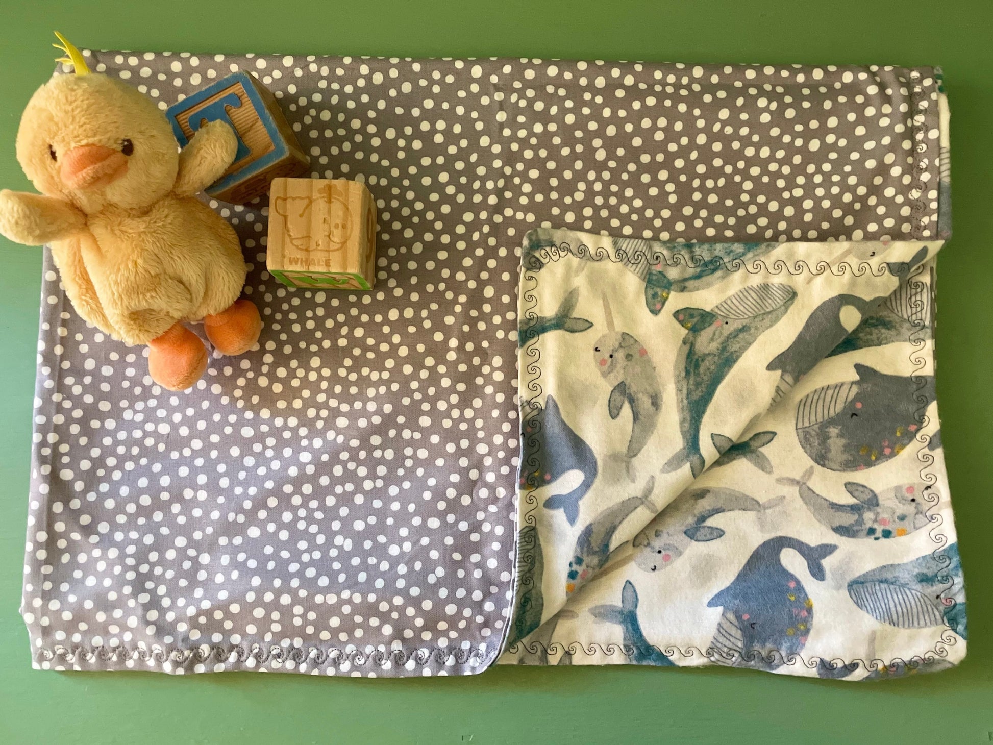 Fabric with whale pattern, polka dot fabric, and plush toy on a green background
