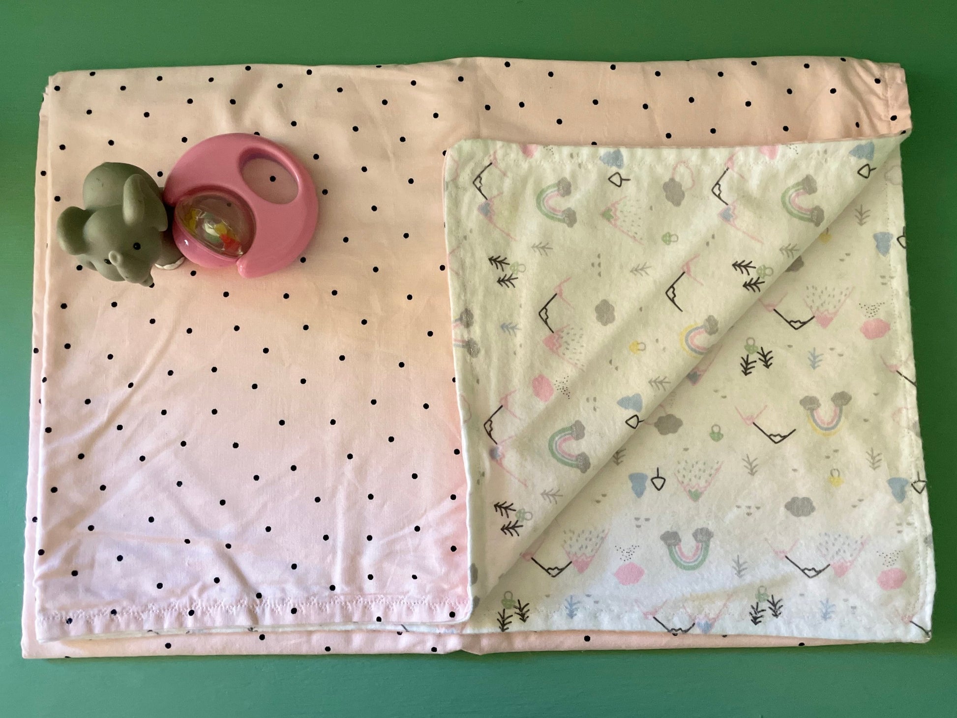 Reversible baby blanket with polka dots on one side and colorful mountain scene on the reverse