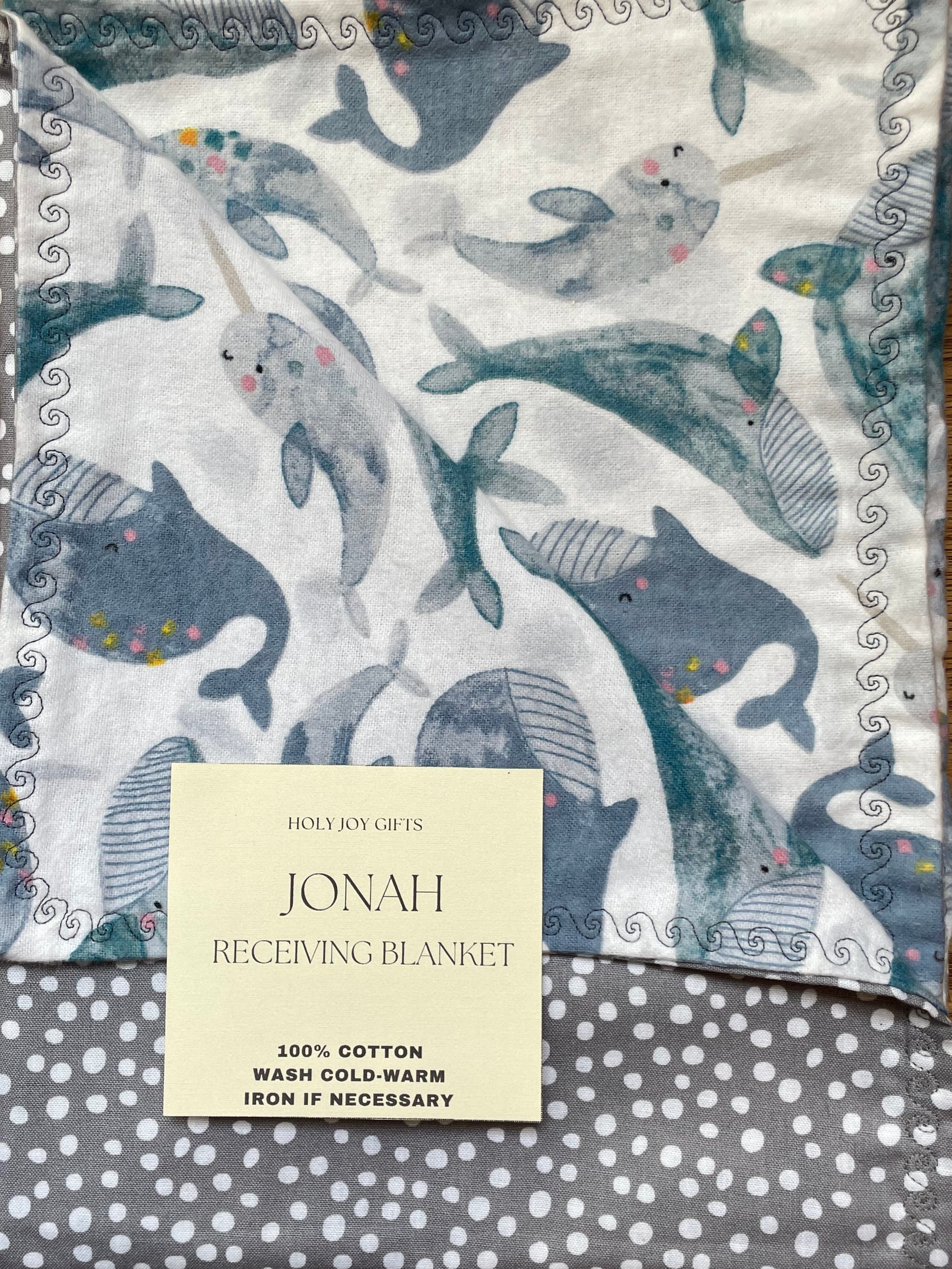 Baby blanket with whale pattern on one side and soft grey and white polkadots on the reverse.