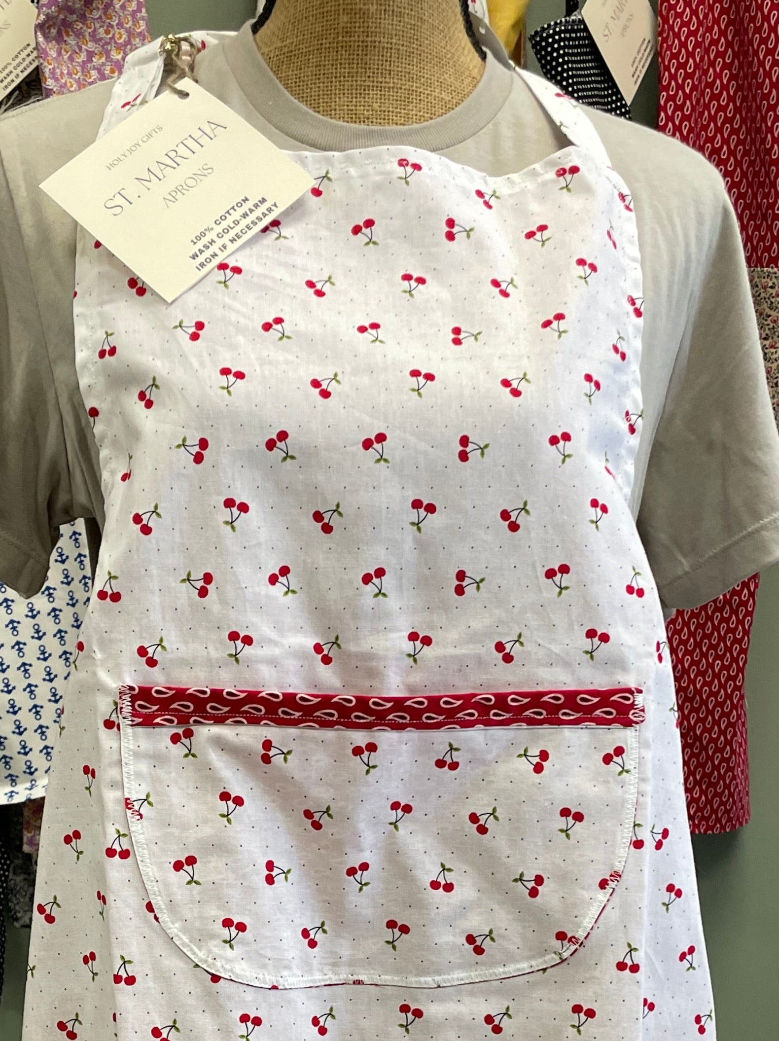 Apron with cherry pattern on a hanger against a neutral background