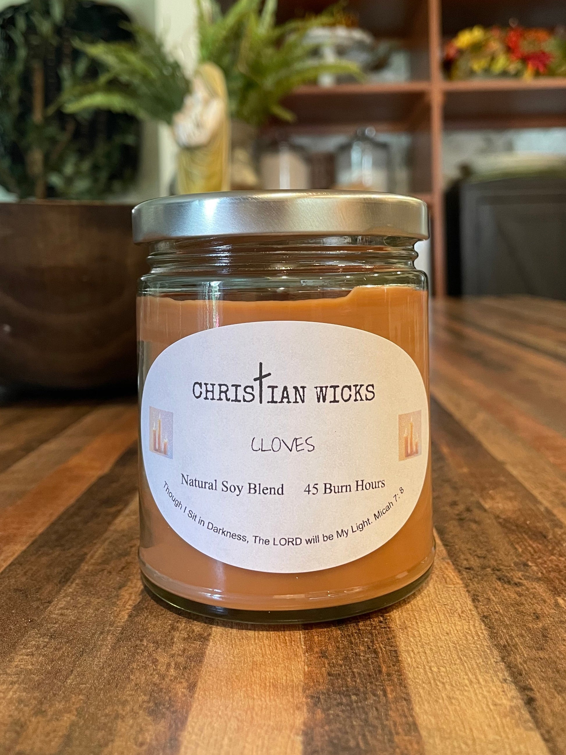 Jar of Christian Wicks product on a wooden surface with a blurred indoor background