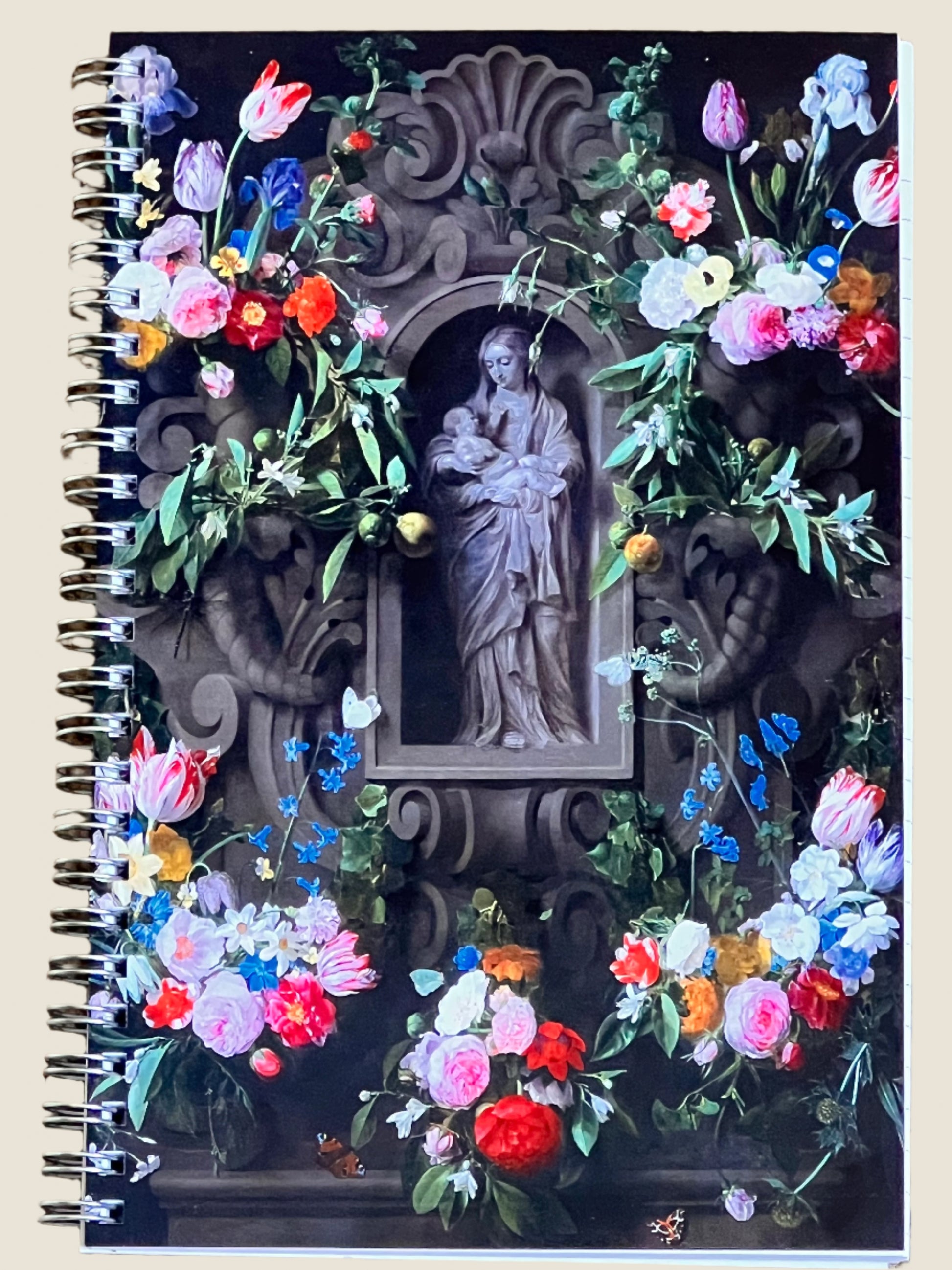 Decorative notebook cover with religious statue and colorful flowers