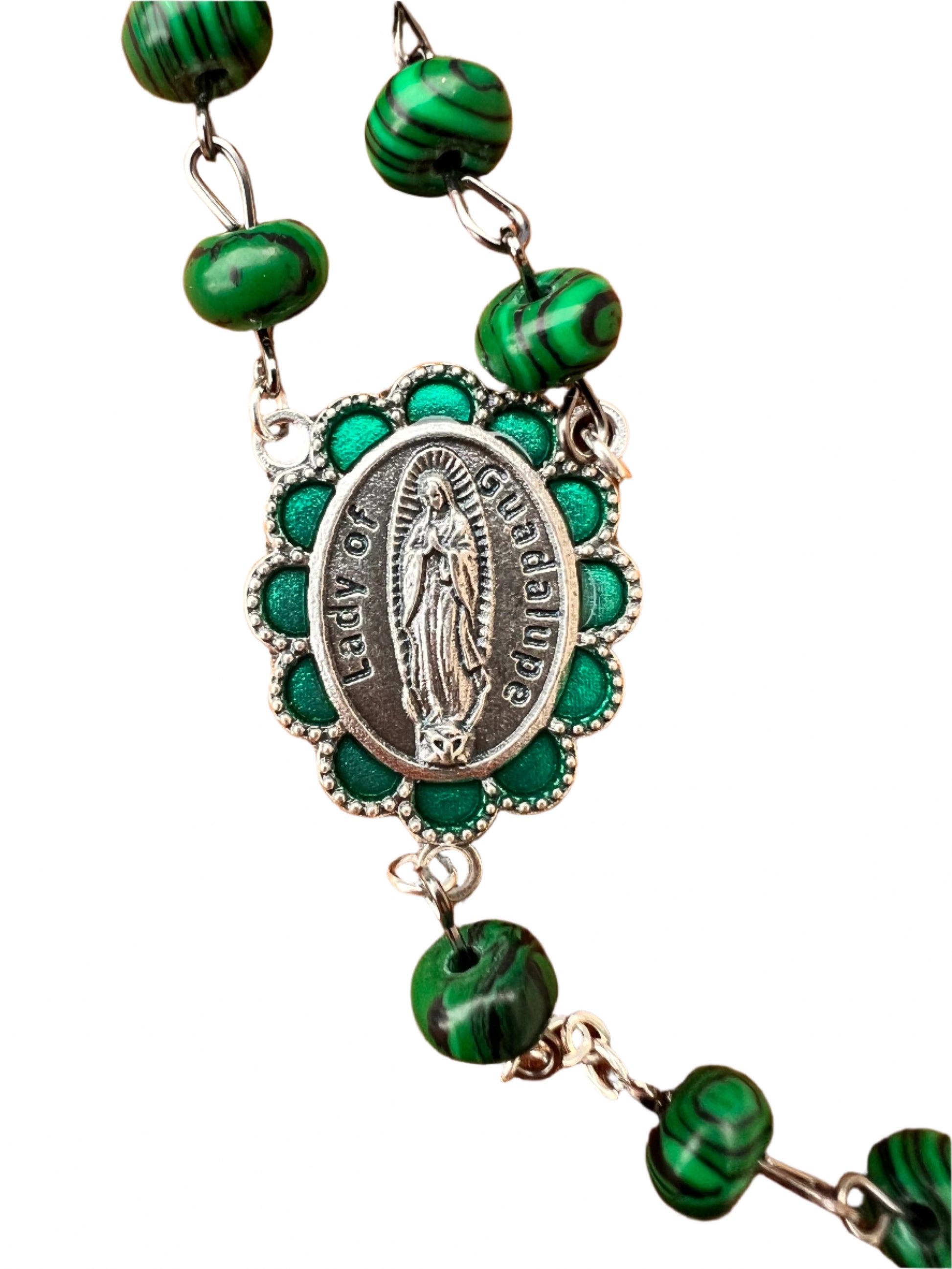 Green beaded Rosary with a silver pendant of Our Lady of Guadalupe on a white background