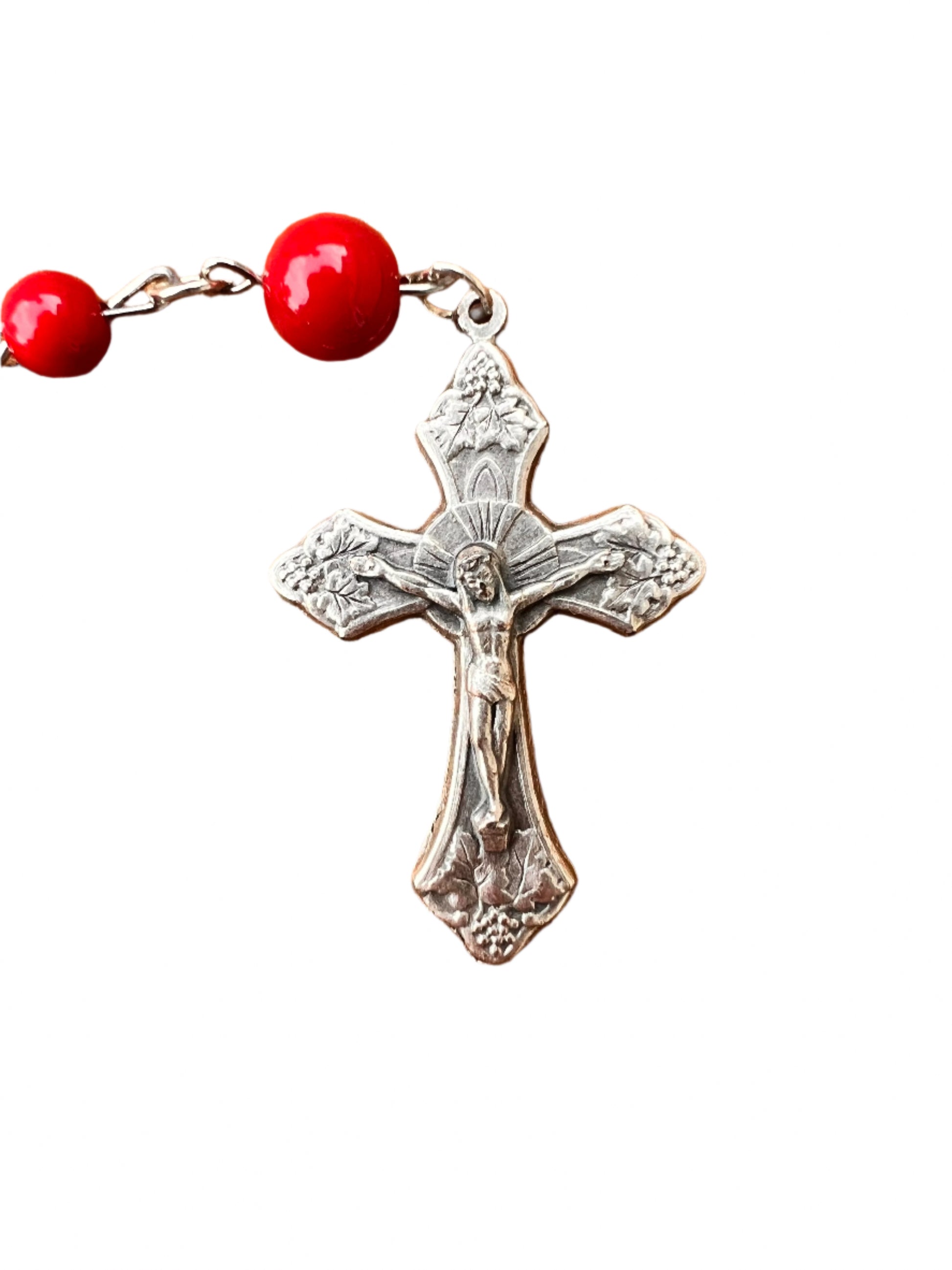 Silver cross with red beads on a wooden surface