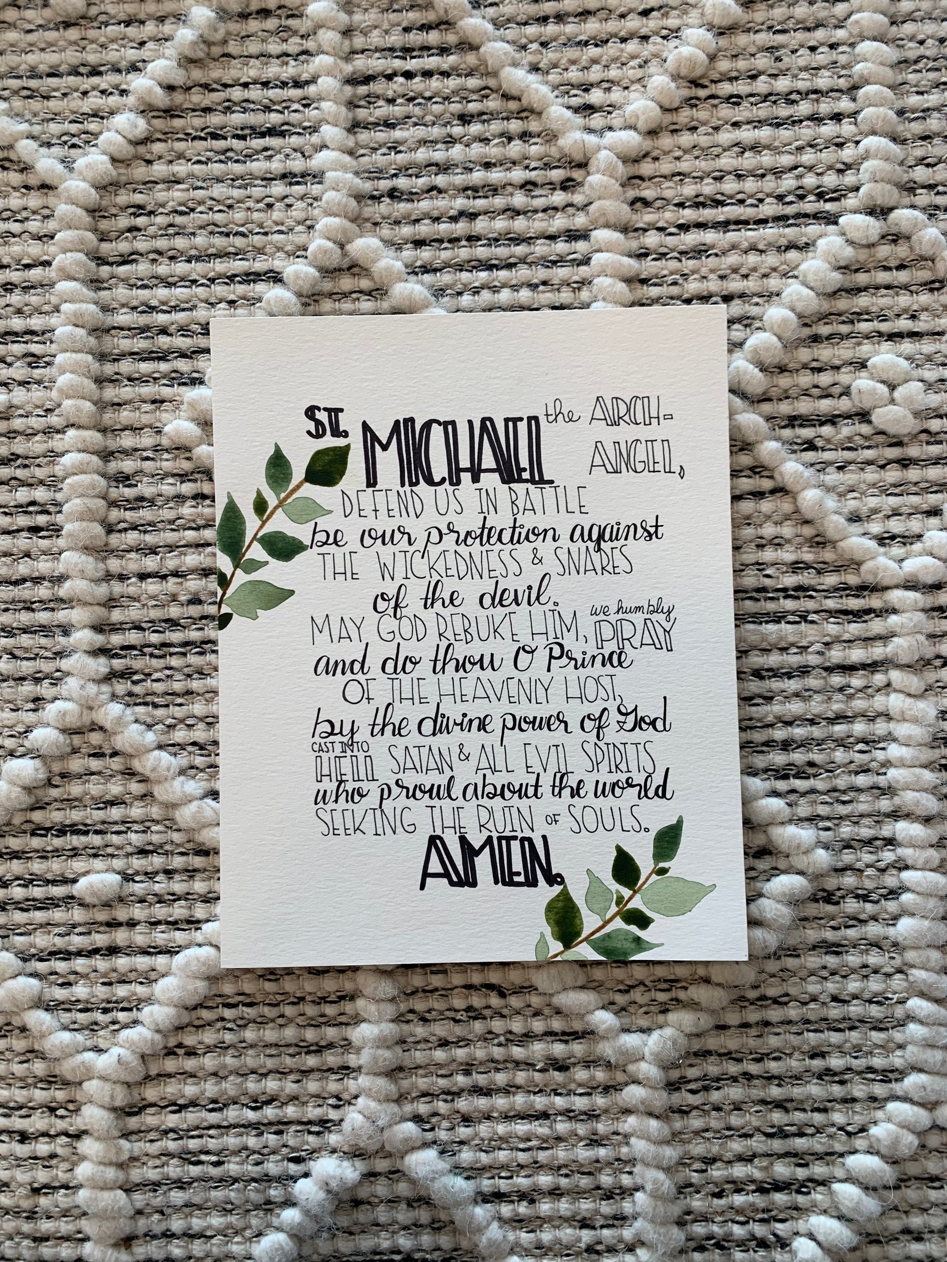 White card with black text and green leaves on a textured beige surface