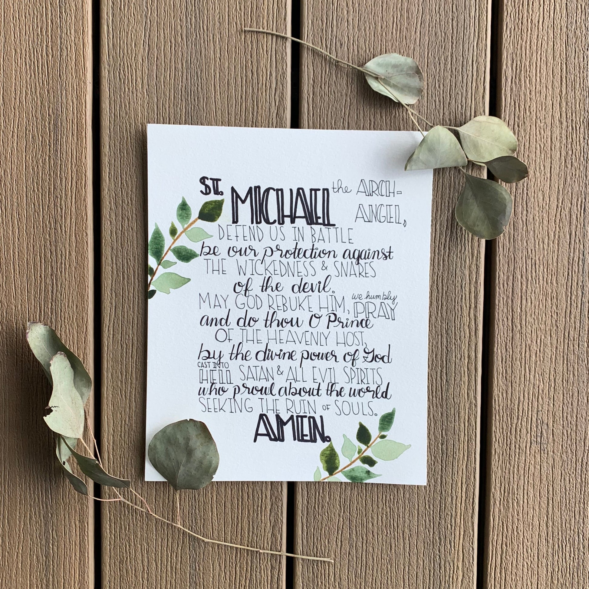 White card with text and green leaves on a wooden surface