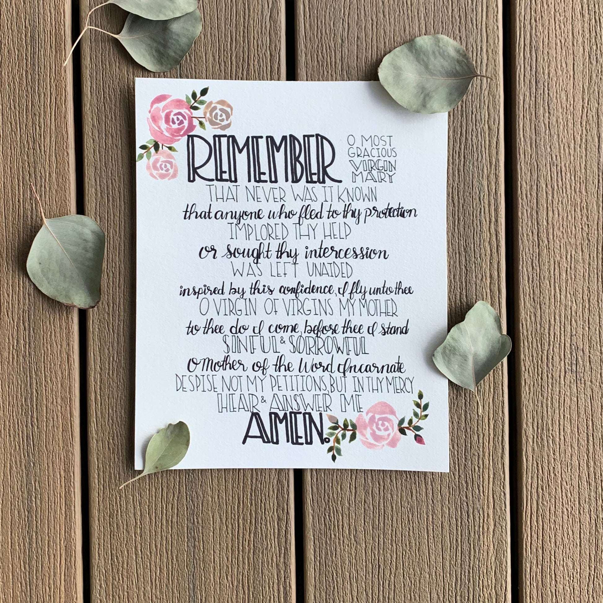 Decorative card with text and floral elements on a wooden surface with leaves.