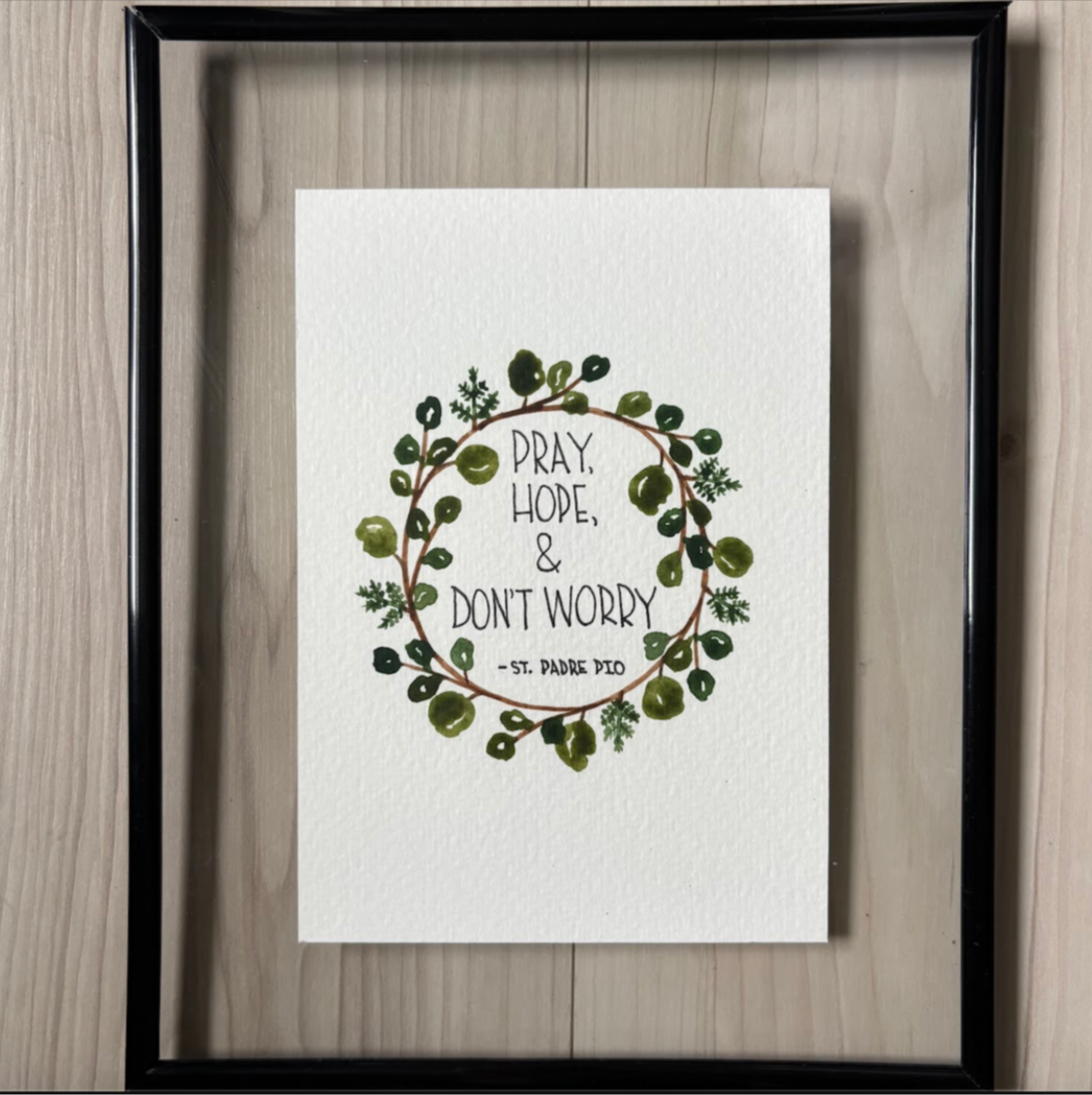 Framed artwork with text from Padre Pio and wreath
