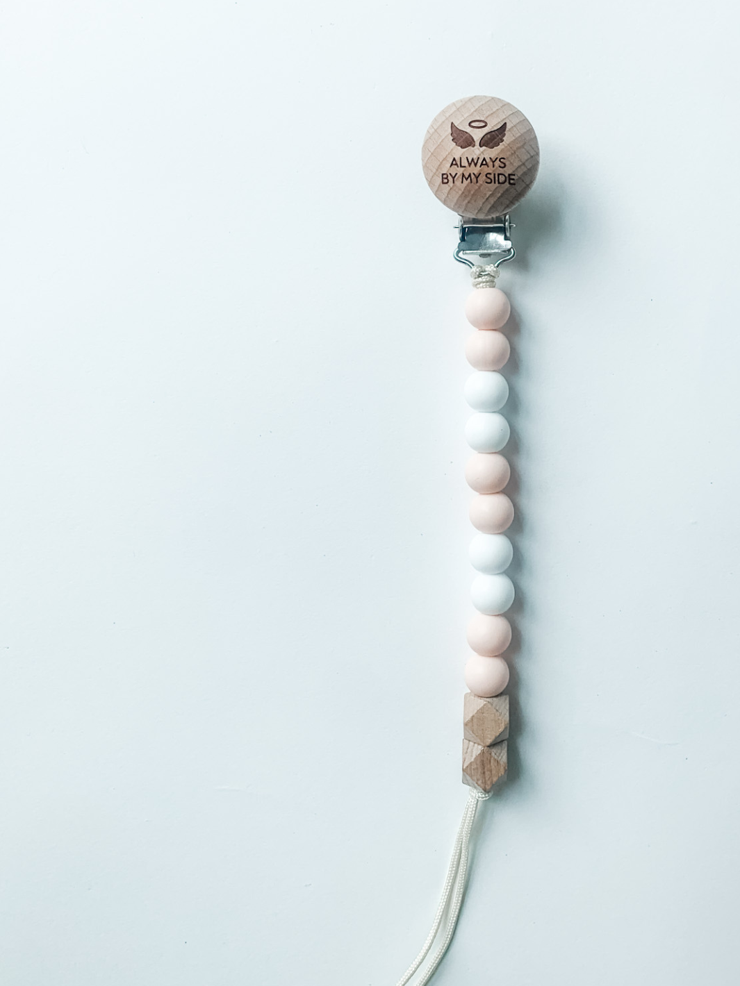 Beaded pacifier clip with wooden holder on a light gray background