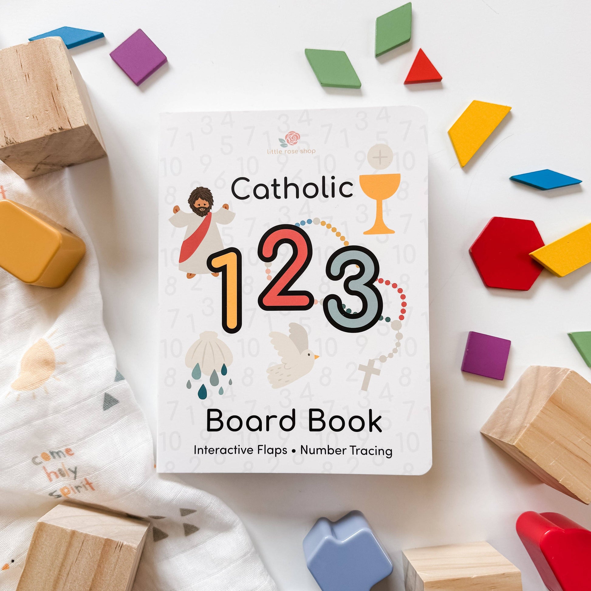 Catholic 123 Board Book surrounded by colorful wooden blocks and geometric shapes on a white background