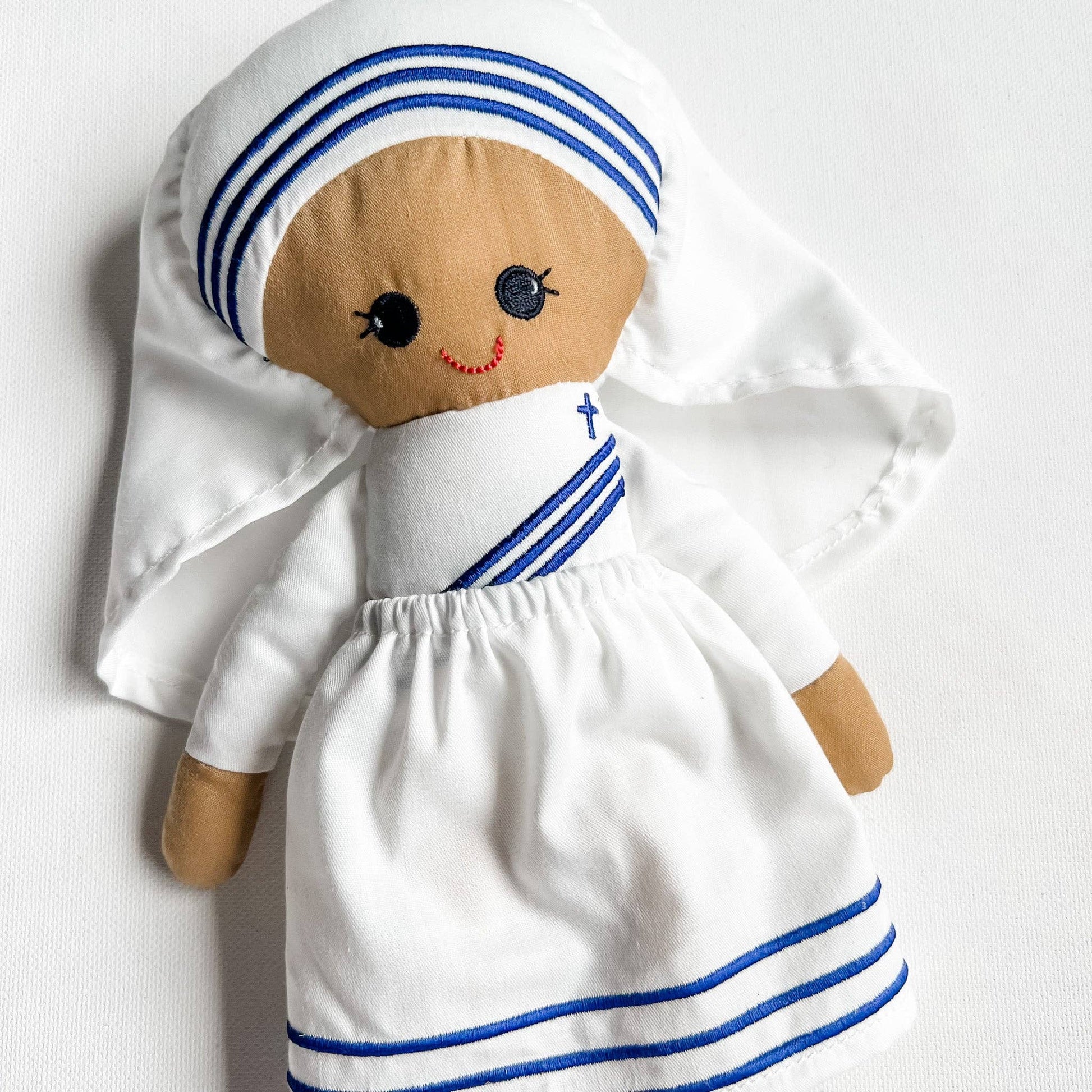 Toy figure of a nun with white dress and blue stripes on a white background