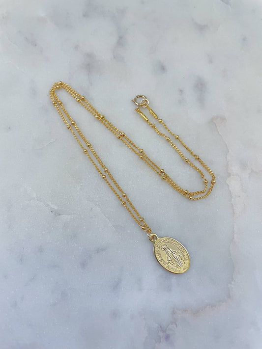 Gold necklace with a pendant on a marble surface