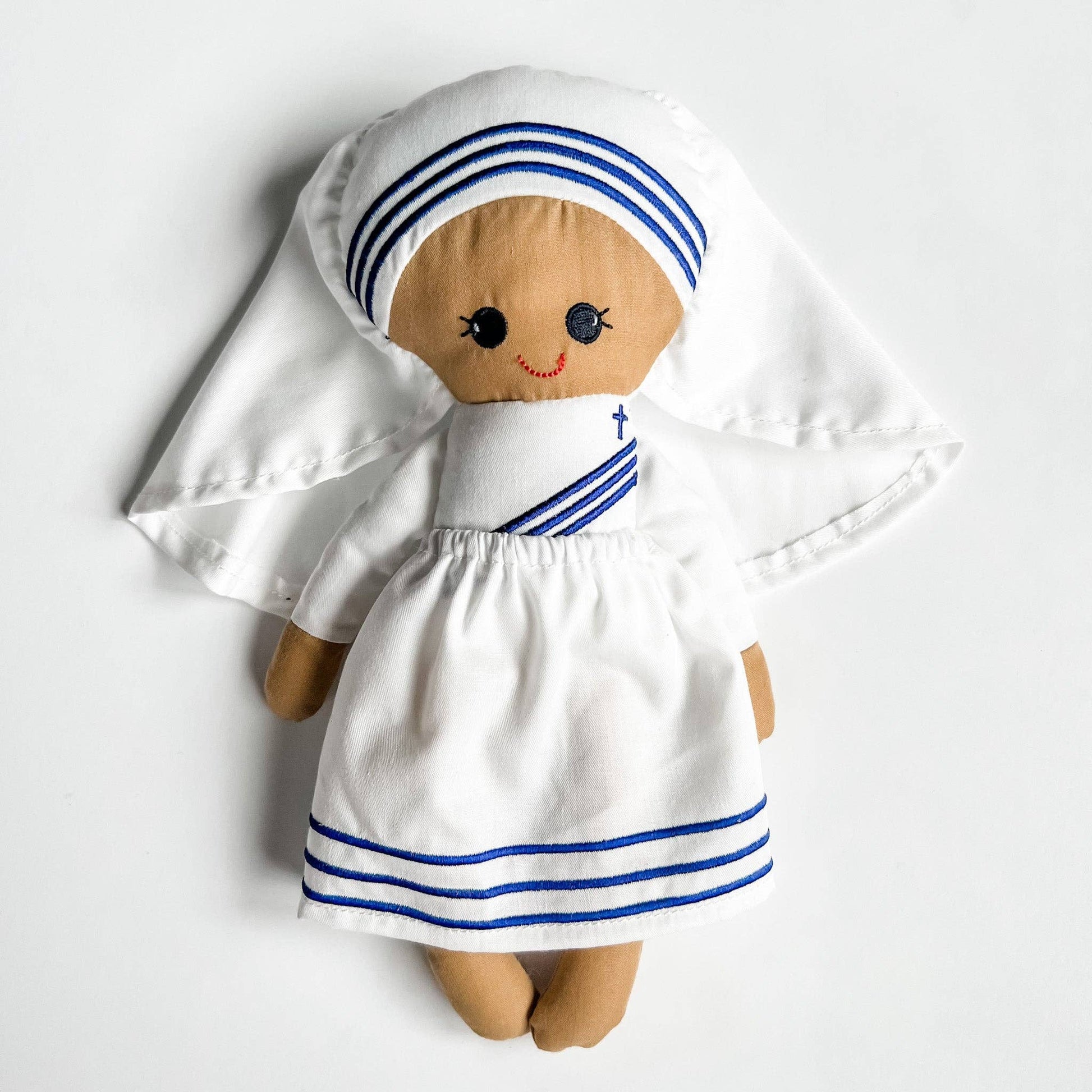Doll dressed in a white outfit with blue stripes on a white background