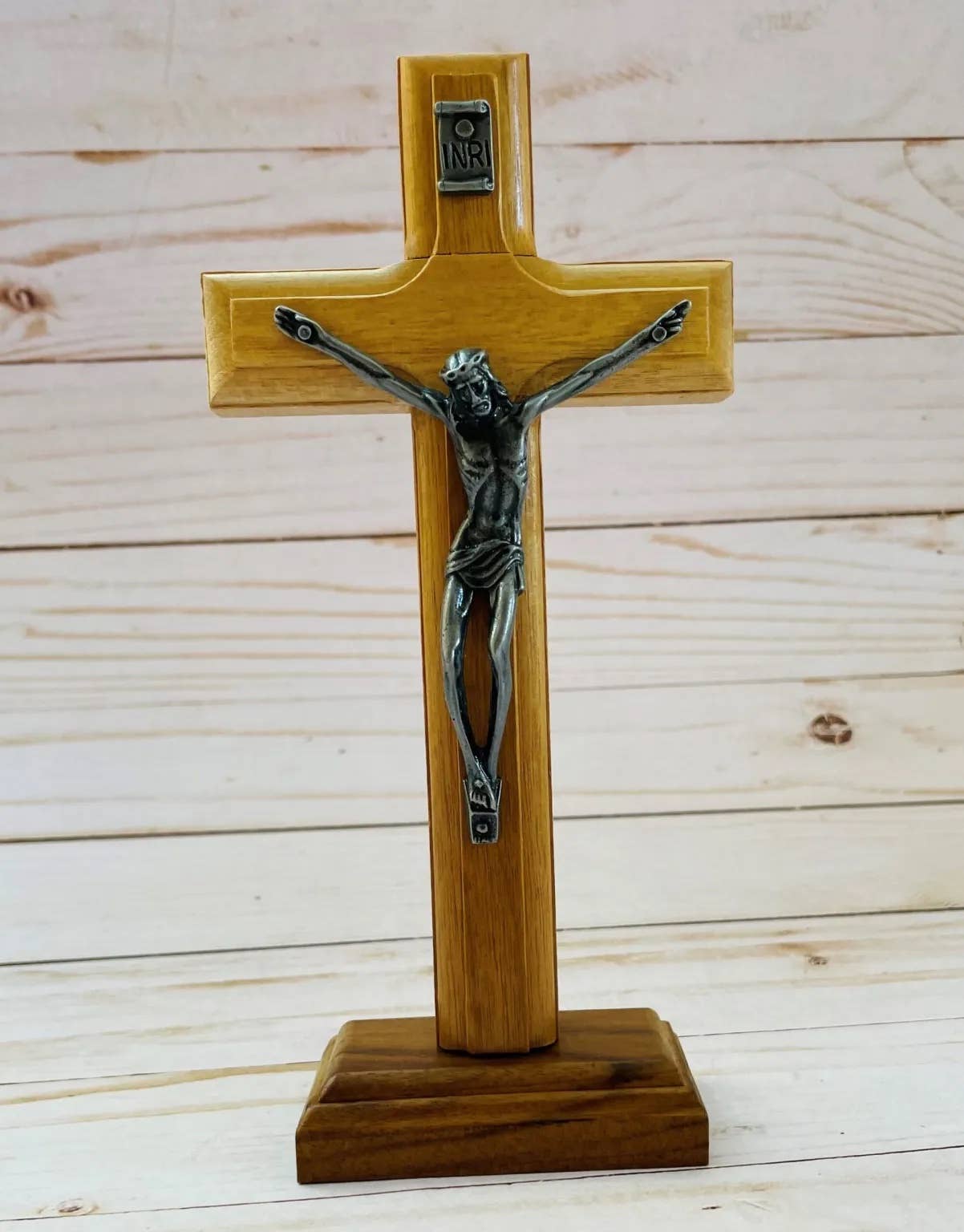 Wooden cross with a metal figure of Jesus on a wooden background
