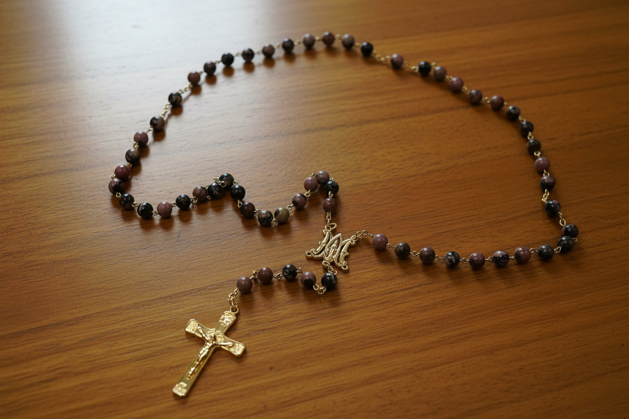 Rosary with brown beads and a gold cross on a light gray background