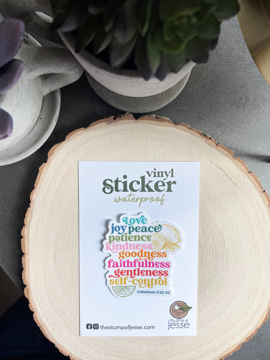 Sticker with fruits of the Holy Spirit on a wooden coaster with a plant in the background