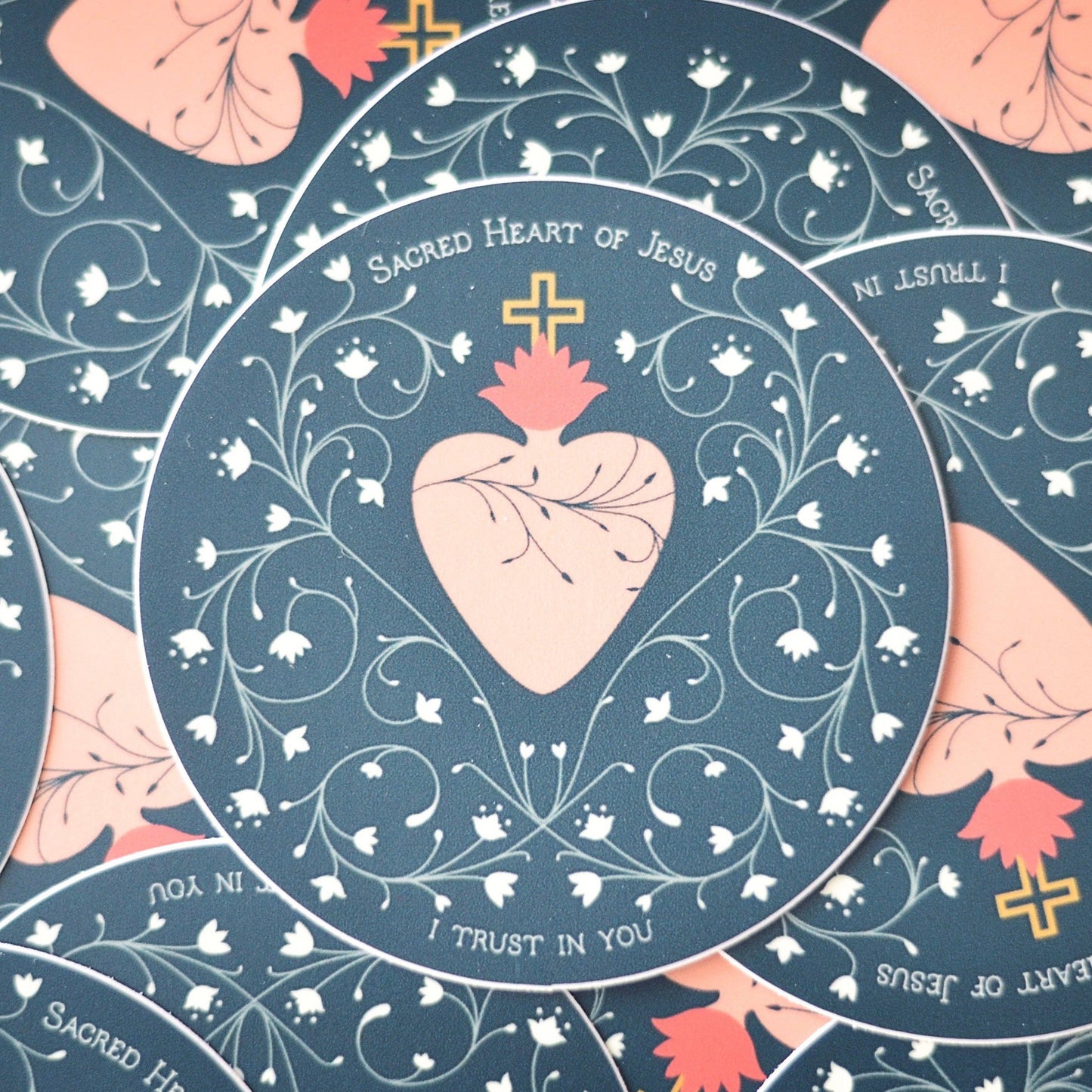 Decorative design with a heart and cross, featuring text 'Sacred Heart of Jesus' and 'I Trust In You', on a blue background.